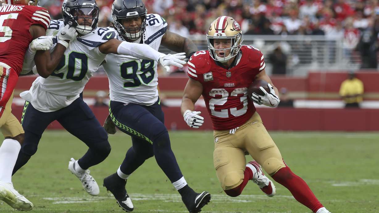 San Francisco 49ers running back Christian McCaffrey (23) runs against Seattle Seahawks safety Julian Love (20) and defensive tackle Roy Robertson-Harris (98) during the second half of an NFL football game in Santa Clara, Calif., Sunday, Nov. 17, 2024.
