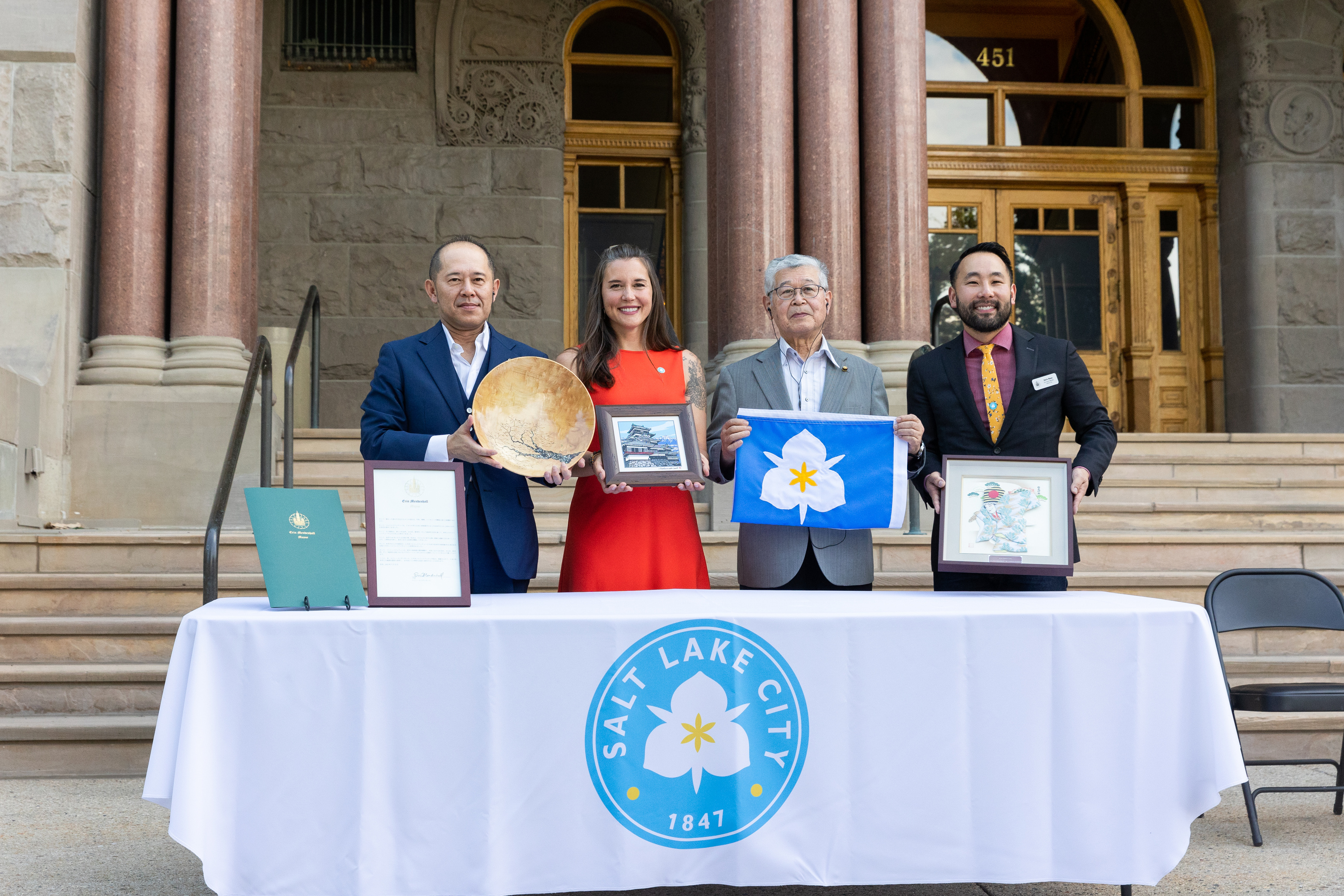 Matsumoto, Japan, Mayor Yoshinao Gaun, from left, Salt Lake City Mayor Erin Mendenhall, Salt Lake City Council Chair Darin Masao Mano and Matsumoto City Council President Yutaka Kamijo smile with the gifts they have been presented outside of the Salt Lake City-County Building in Salt Lake City on July 23, 2023. The event commemorated the 65th anniversary of the sister city relationship with the two cities.