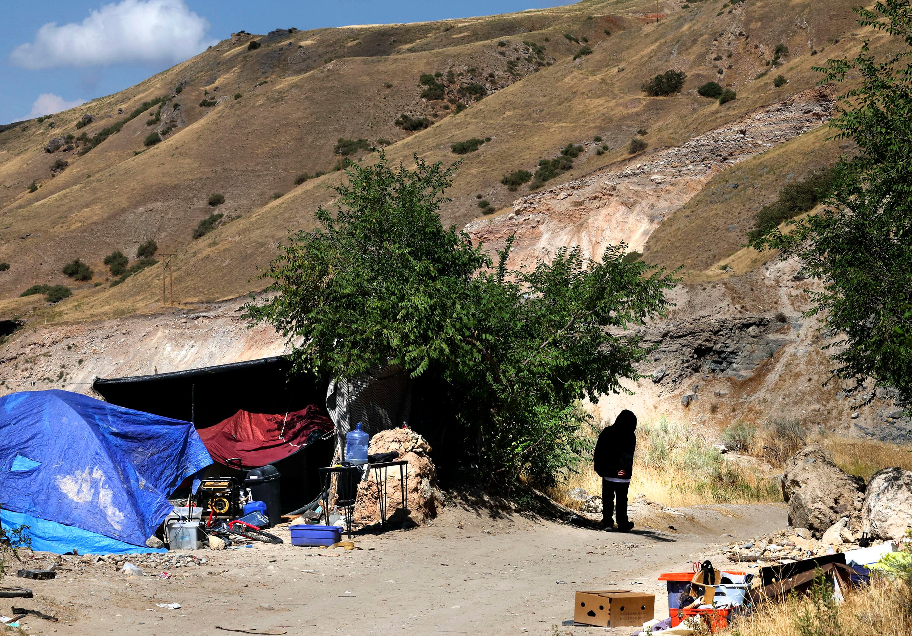 A man walks past a homeless camp located above Victory Road in Salt Lake City on Sept. 15, 2022.