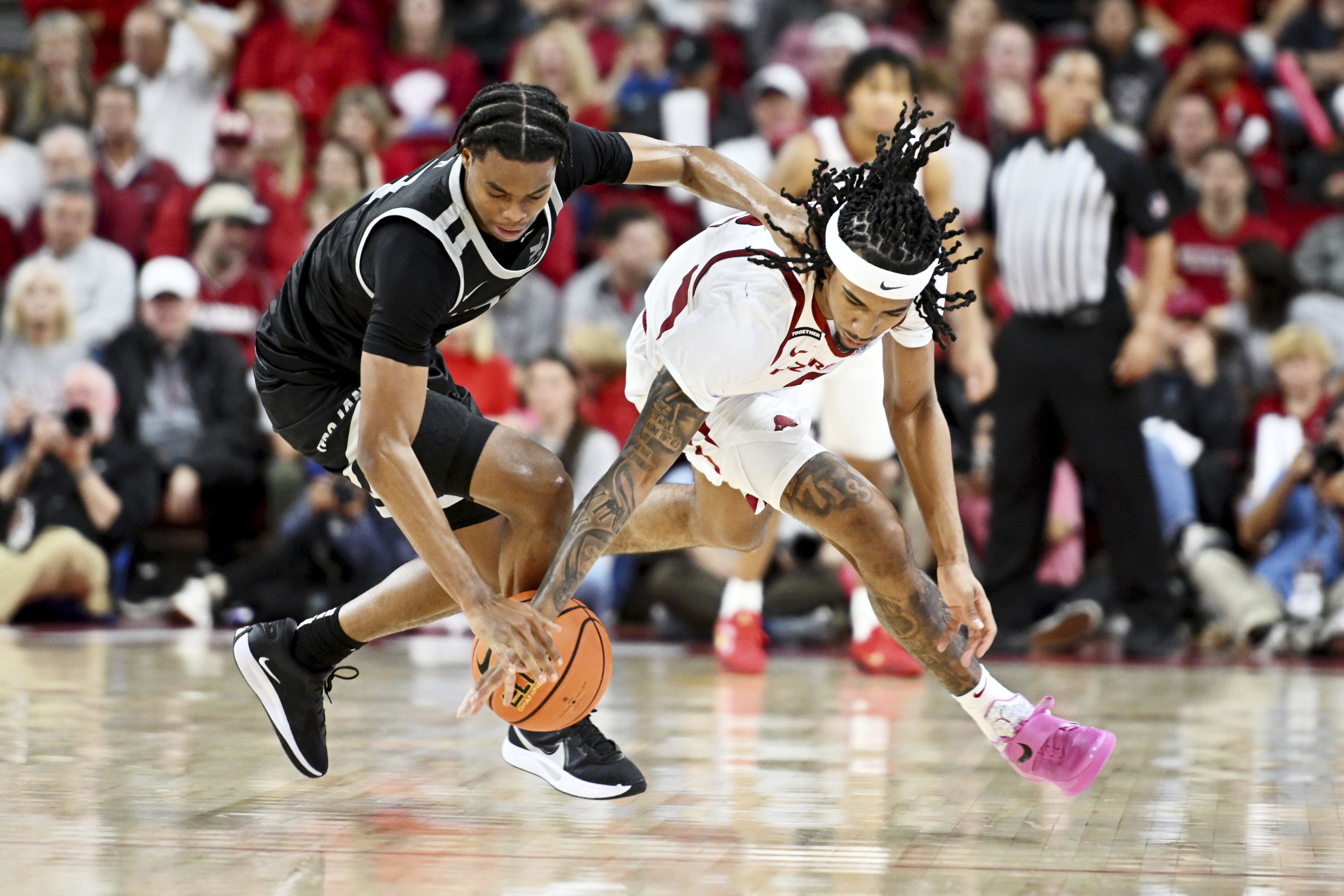 Little Rock guard Isaiah Lewis, left, and Arkansas guard Boogie Fland, right, go after a loose ball during the second half of an NCAA college basketball game Friday, Nov. 22, 2024, in Fayetteville, Ark.