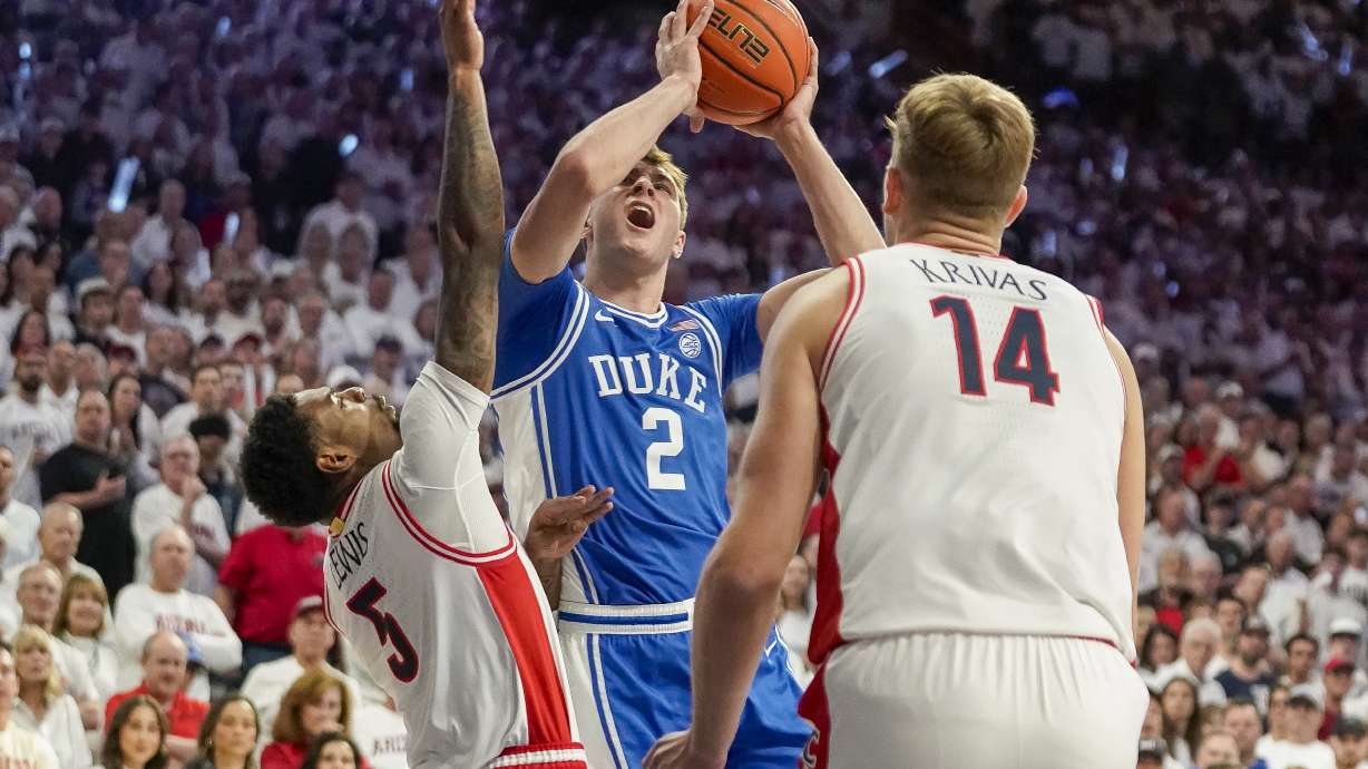 Duke guard Cooper Flagg (2) is double-teamed by Arizona guard KJ Lewis (5) and Motiejus Krivas (14) during the first half of an NCAA college basketball game Friday, Nov. 22, 2024, in Tucson, Ariz.