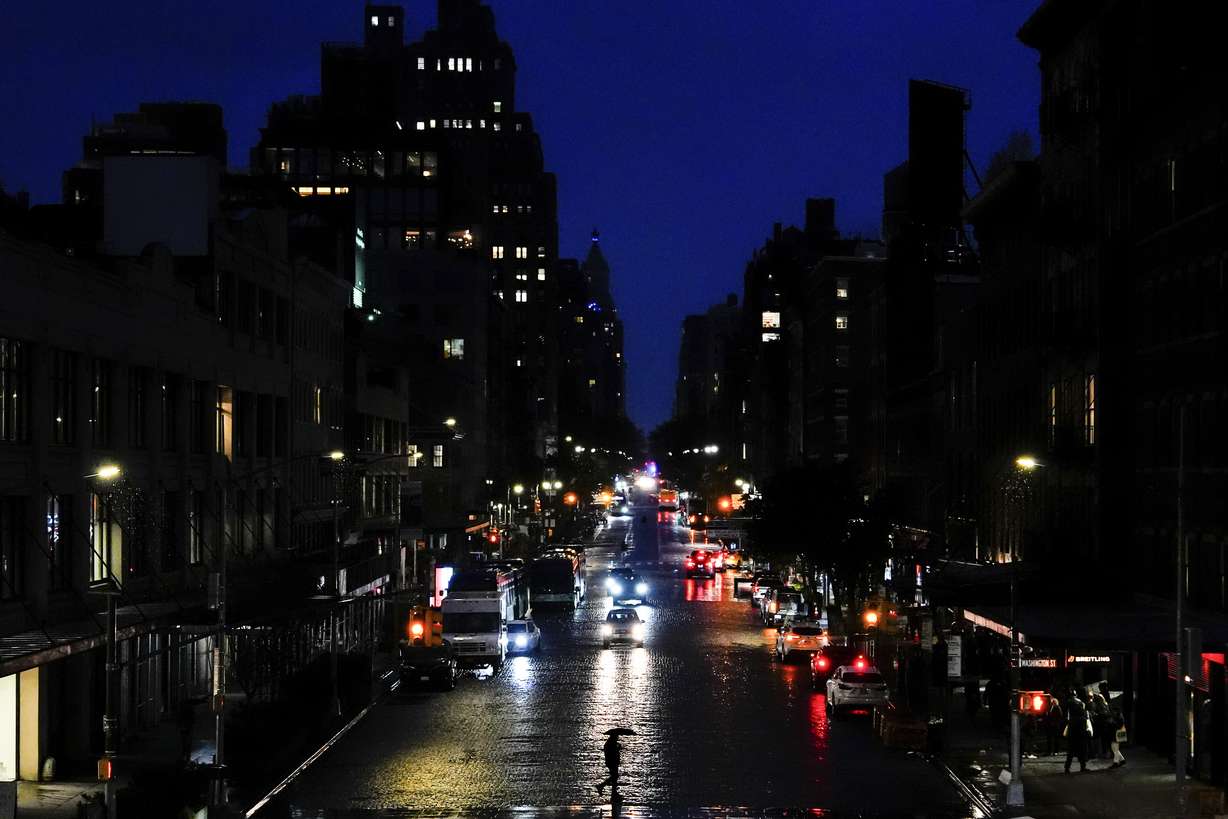 A person uses an umbrella while crossing a street in the Meatpacking District neighborhood of Manhattan, Friday, in New York.