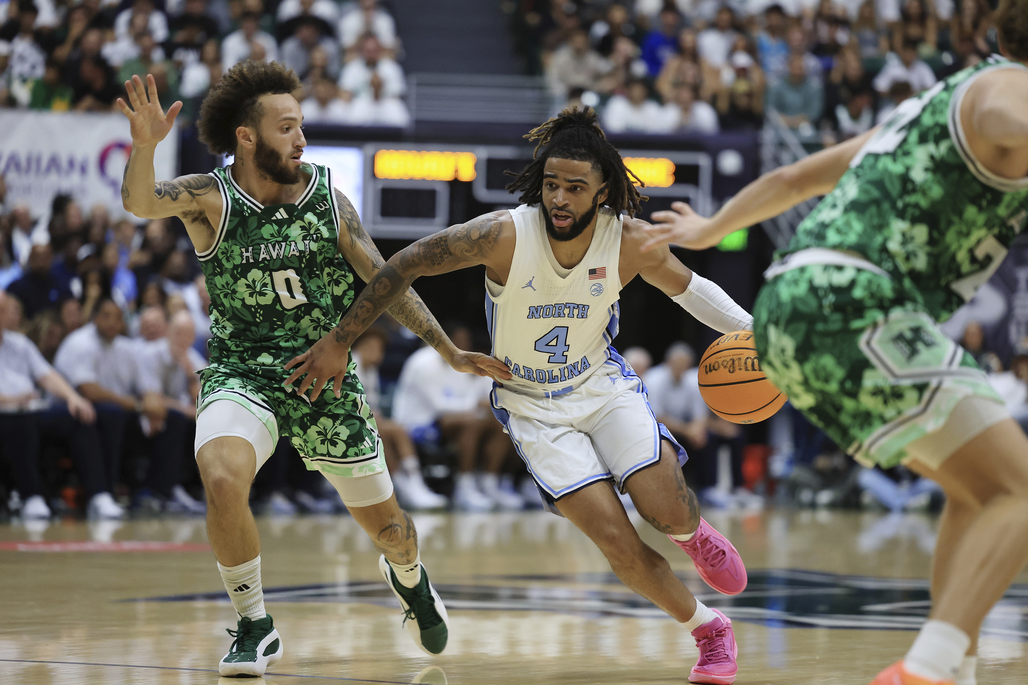 North Carolina guard RJ Davis (4) dribbles past Hawaii guard Kody Williams (0) during the second half of an NCAA college basketball game, Friday, Nov. 22, 2024, in Honolulu. 