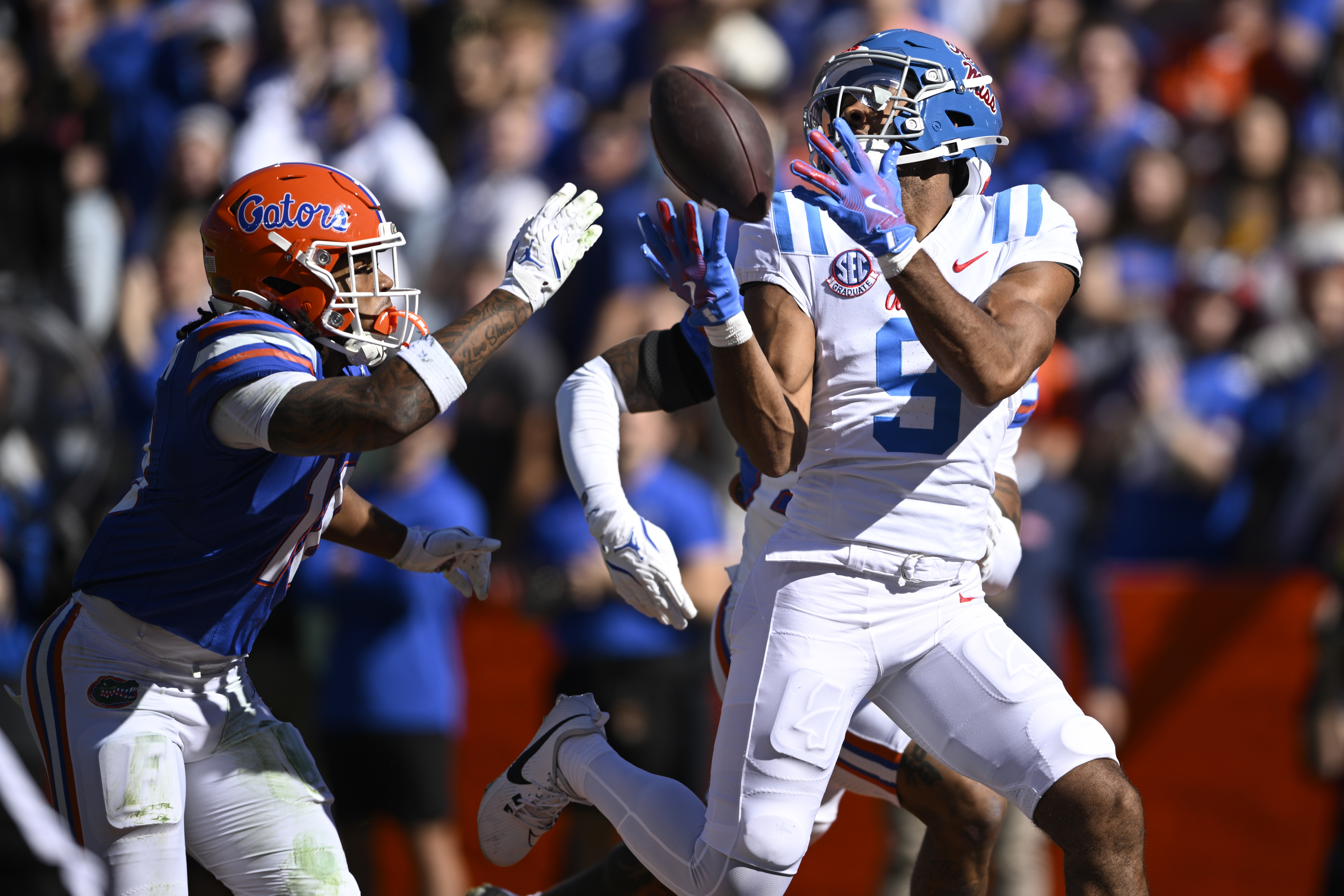 Mississippi wide receiver Tre Harris (9) catches a pass in front of Florida defensive backs Bryce Thornton, left, and Dijon Johnson (obscured at rear) for a 43-yard touchdown during the first half of an NCAA college football game, Saturday, Nov. 23, 2024, in Gainesville, Fla.