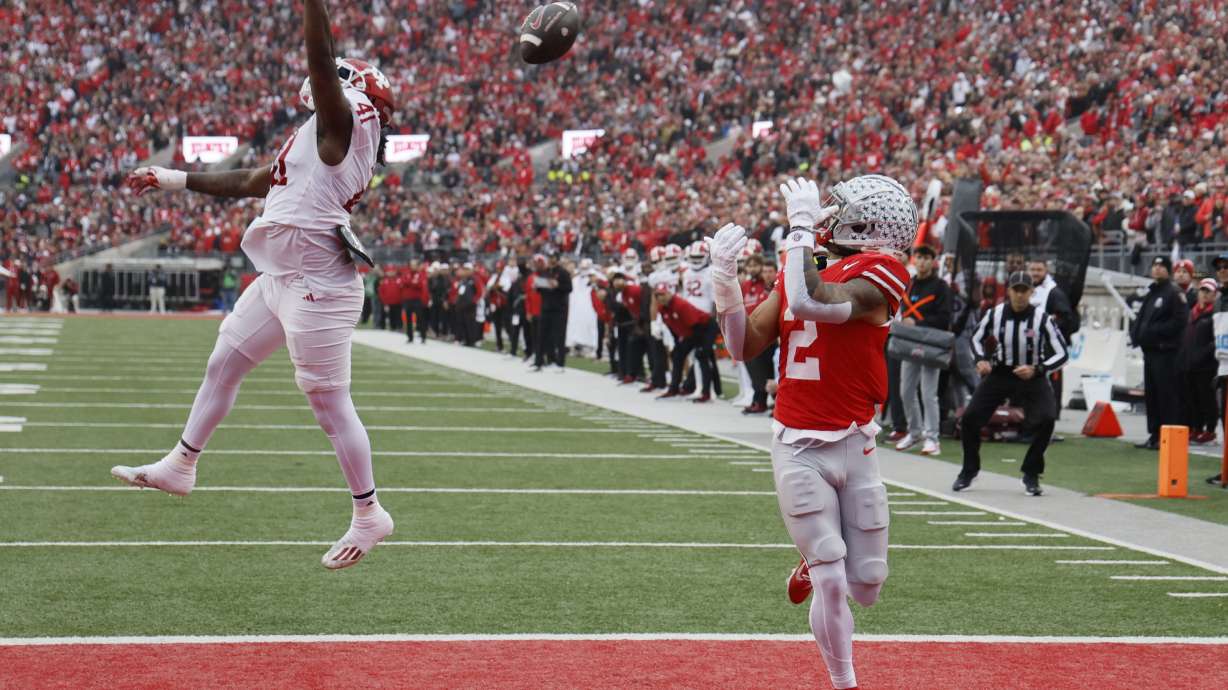 Ohio State receiver Emeka Egbuka, right, catches a touchdown pass thrown over Indiana defensive lineman Lanell Carr during the first half of an NCAA college football game Saturday, Nov. 23, 2024, in Columbus, Ohio.