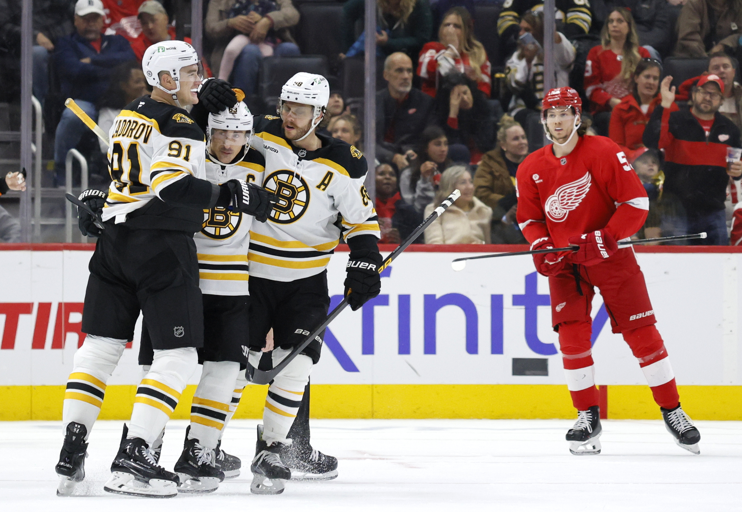 Boston Bruins left wing Brad Marchand, second from left, celebrates with defenseman Nikita Zadorov (91) and right wing David Pastrnak (88) after scoring the winning goal as Detroit Red Wings defenseman Moritz Seider (53) skates off during the third period of an NHL hockey game Saturday, Nov. 23, 2024, in Detroit. 