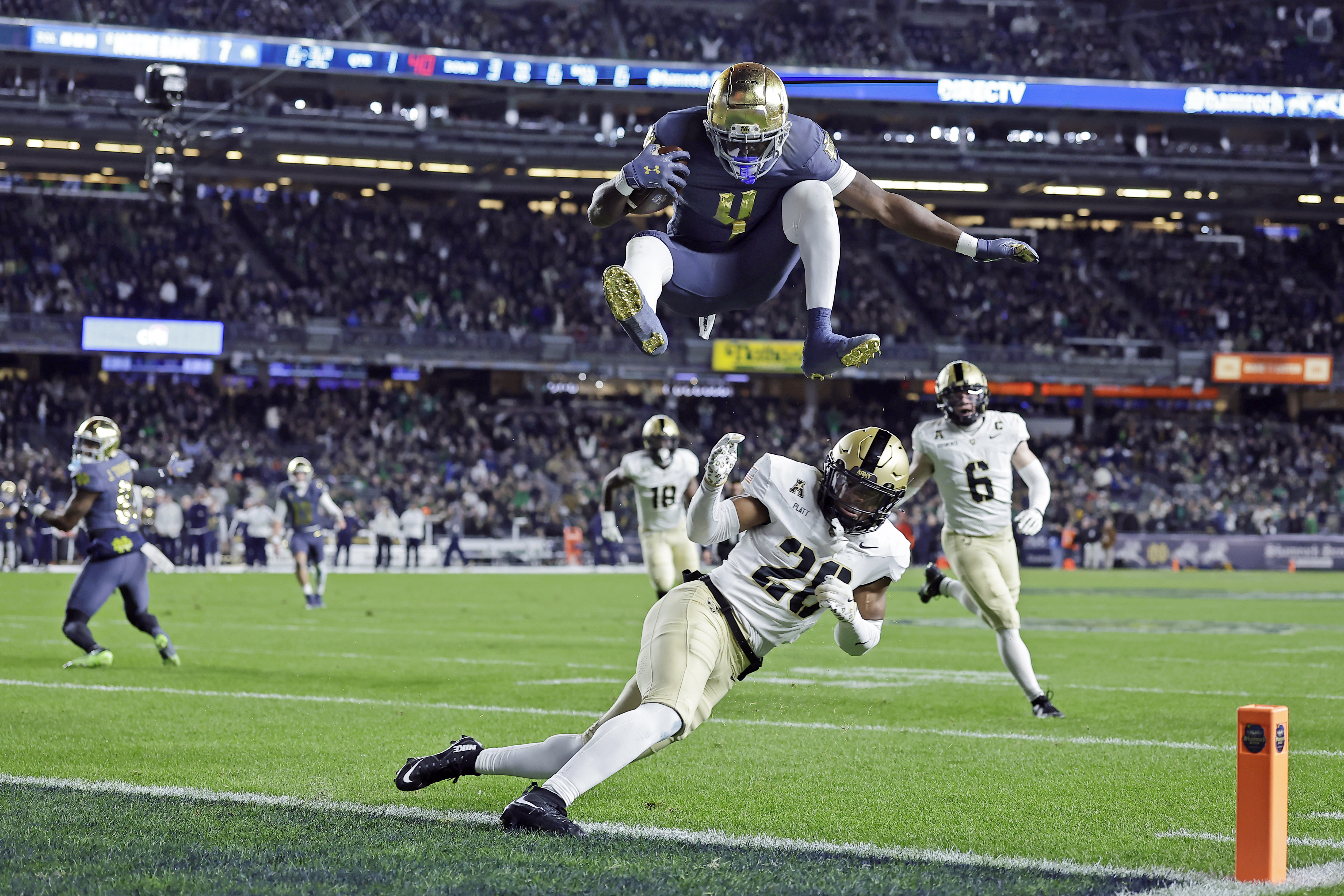 Notre Dame running back Jeremiyah Love (4) leaps over Army cornerback Donavon Platt to score a touchdown during the first half of an NCAA college football game at Yankee Stadium, Saturday, Nov. 23, 2024, in New York.