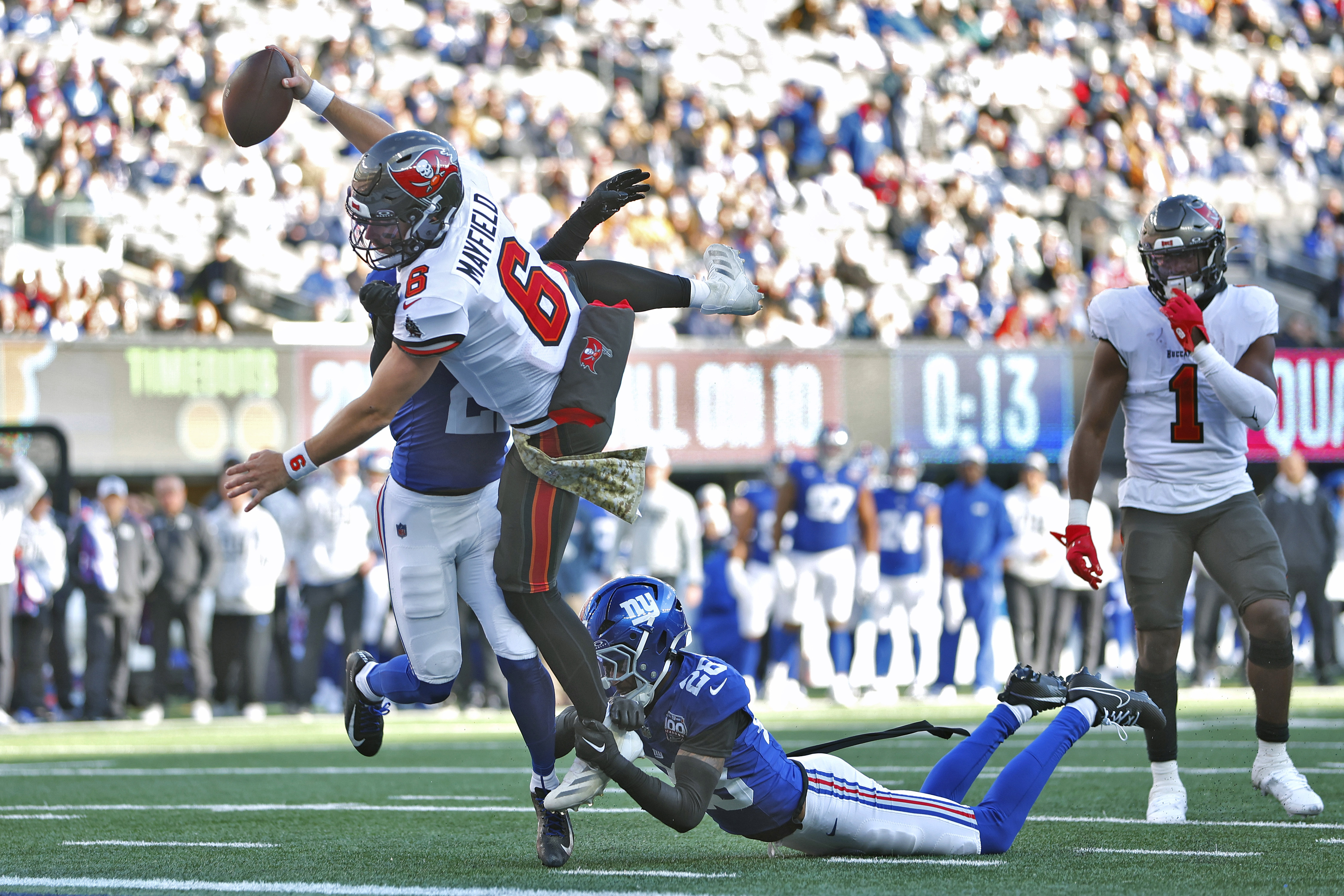 Tampa Bay Buccaneers quarterback Baker Mayfield (6) scores past New York Giants cornerback Dru Phillips (22) and cornerback Cor'Dale Flott (28) during the first half of an NFL football game Sunday, Nov. 24, 2024, in East Rutherford, N.J. 