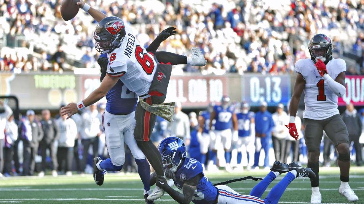 Tampa Bay Buccaneers quarterback Baker Mayfield (6) scores past New York Giants cornerback Dru Phillips (22) and cornerback Cor'Dale Flott (28) during the first half of an NFL football game Sunday, Nov. 24, 2024, in East Rutherford, N.J.