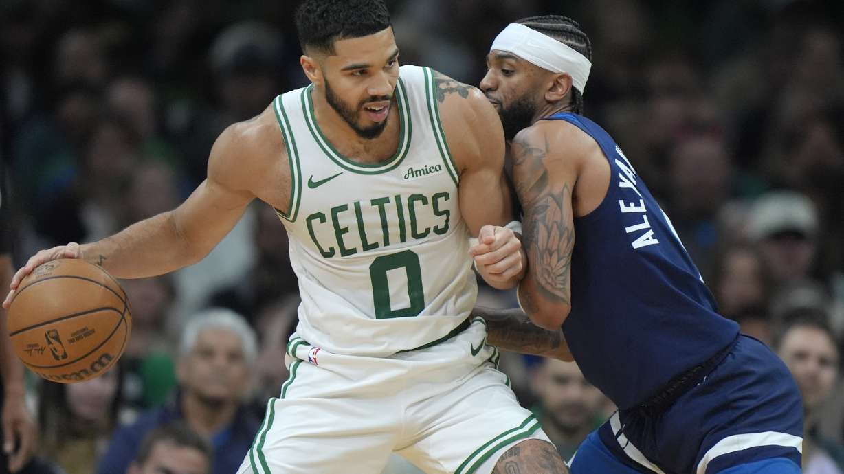 Boston Celtics forward Jayson Tatum (0) looks for an opening around Minnesota Timberwolves guard Nickeil Alexander-Walker, right, in the first half of an NBA basketball game, Sunday, Nov. 24, 2024, in Boston.