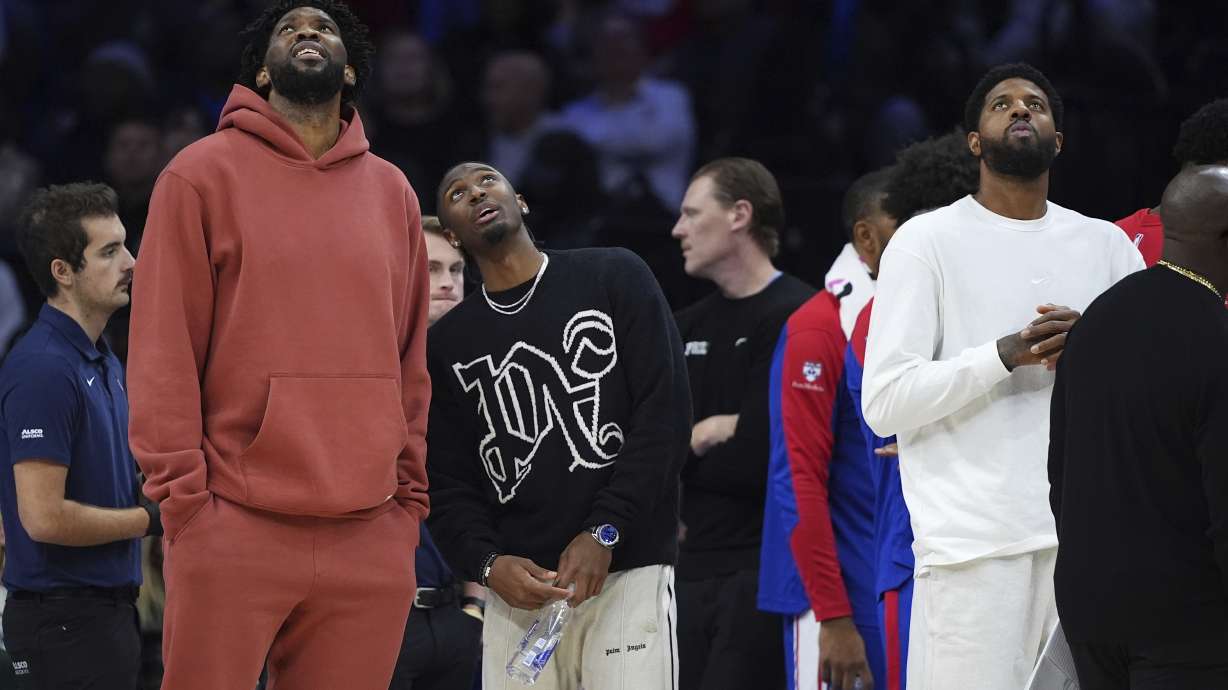 Philadelphia 76ers' Joel Embiid, from left, Tyrese Maxey and Paul George look towards the scoreboard during a timeout during the first half of an NBA basketball game against the Cleveland Cavaliers, Wednesday, Nov. 13, 2024, in Philadelphia.