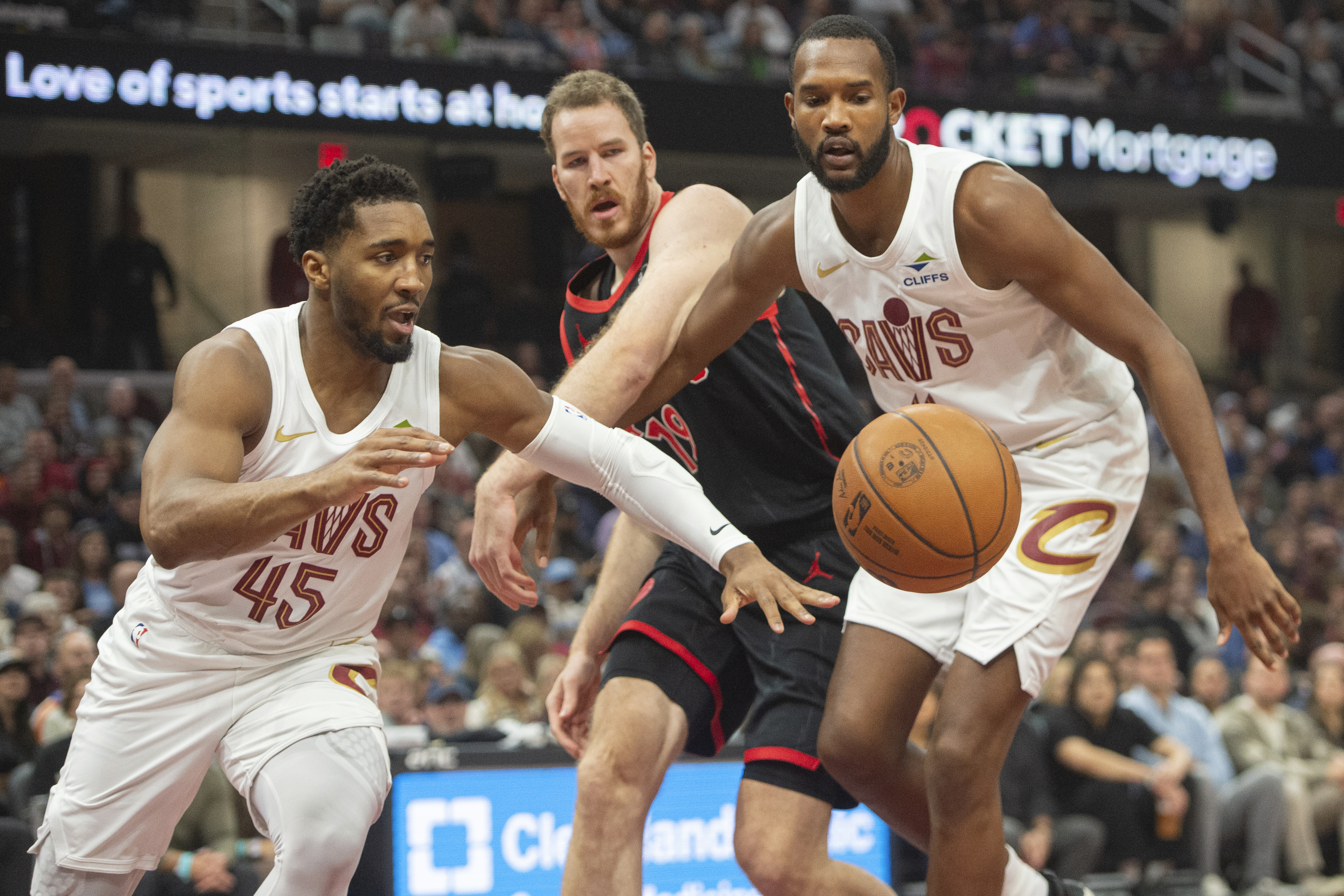 Cleveland Cavaliers' Donovan Mitchell (45) Toronto Raptors' Jakob Poeltl, center and Evan Mobley, right, go for a loose ball during the first half of an NBA basketball game in Cleveland, Sunday, Nov 24, 2024.