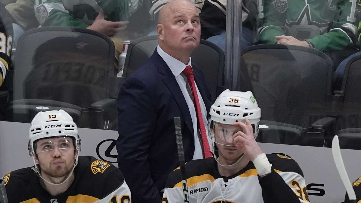 FILE - Boston Bruins head coach Jim Montgomery looks on from the bench with centers John Beecher (19) and Patrick Brown (38) during the first period of an NHL hockey game against the Dallas Stars, Nov. 14, 2024, in Dallas.