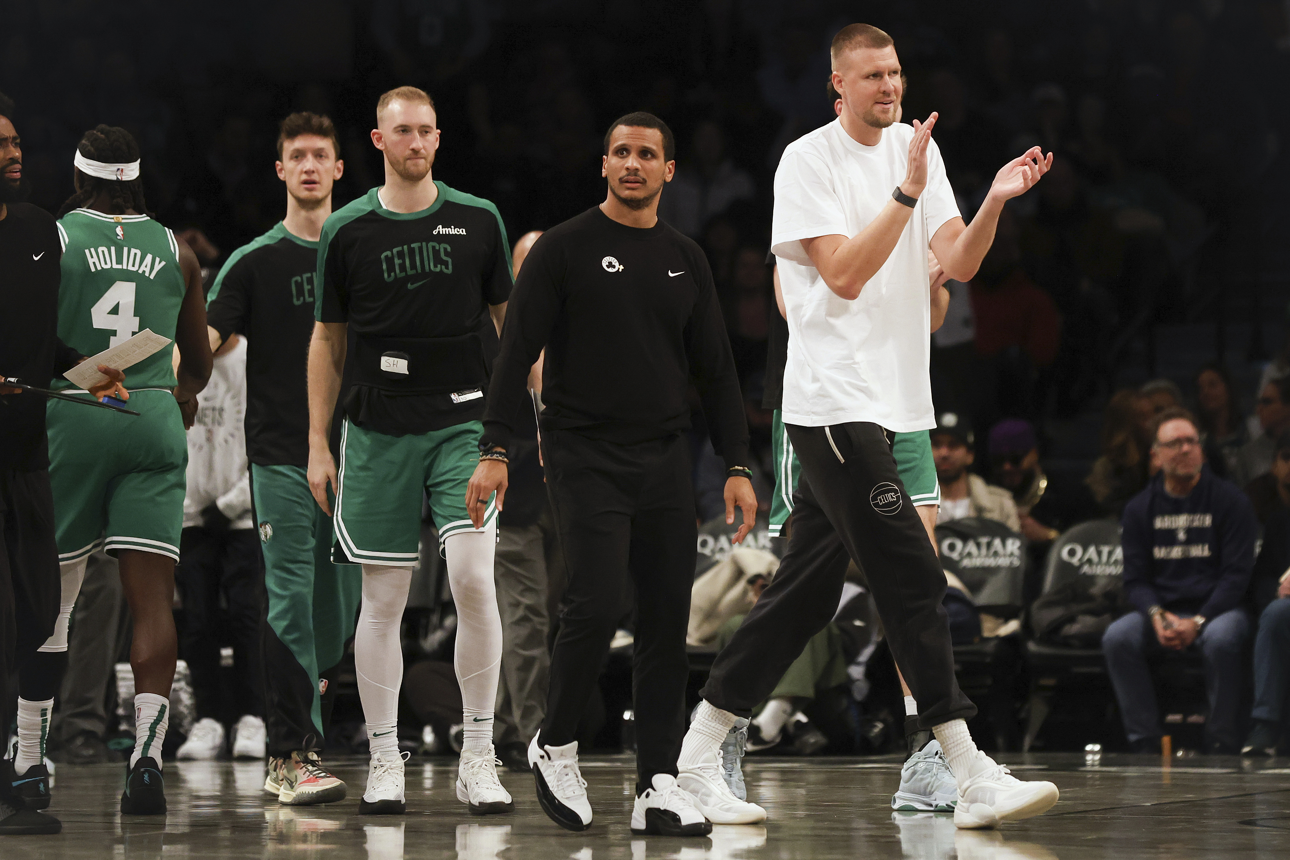 Injured Boston Celtics' center Kristaps Porzingis claps for his teammates in the second half of an NBA basketball game against the Brooklyn Nets, Wednesday, Nov. 13, 2024, in New York.