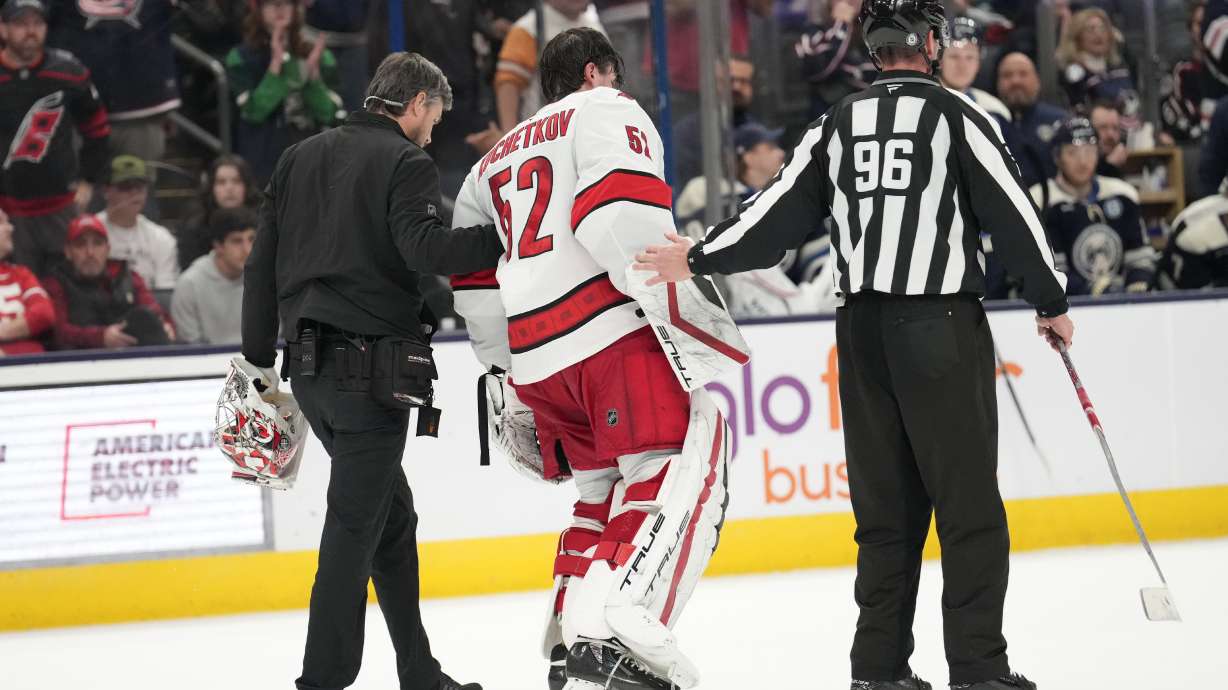 Carolina Hurricanes goaltender Pyotr Kochetkov (52) is helped off the ice by head athletic trainer Doug Bennett, left, and linesman David Brisebois (96) after an injury in overtime of an NHL hockey game against the Columbus Blue Jackets in Columbus, Saturday, Nov. 23, 2024.