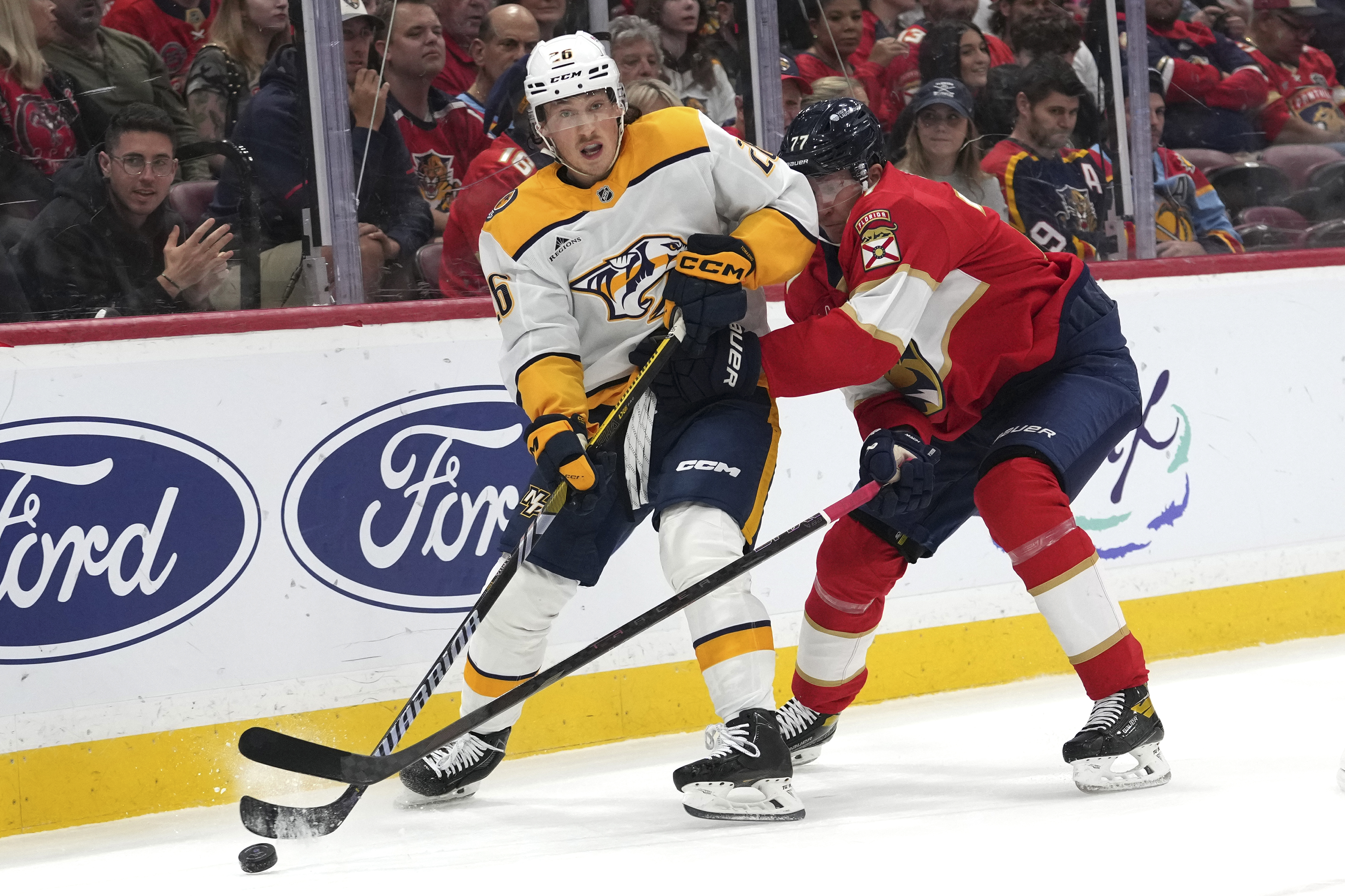 Nashville Predators center Philip Tomasino, left, skates with the puck as Florida Panthers defenseman Niko Mikkola, right, defends during the first period of an NHL hockey game, Thursday, Nov. 7, 2024, in Sunrise, Fla.