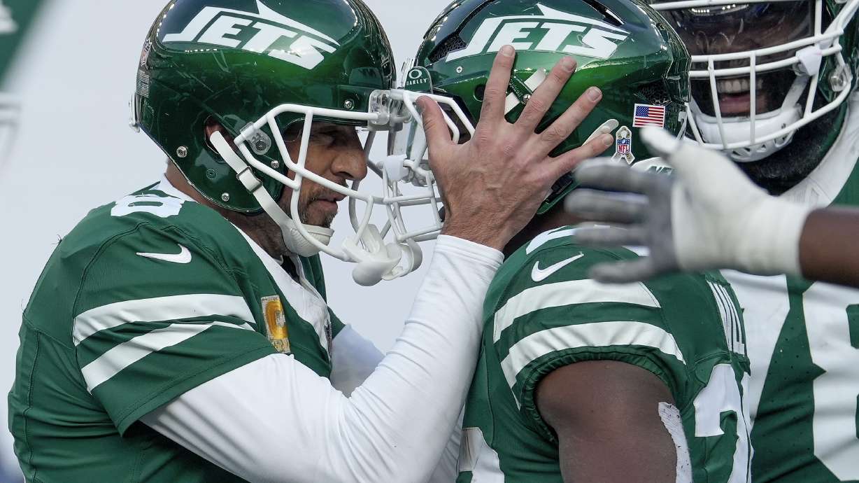 New York Jets quarterback Aaron Rodgers (8) congratulates running back Breece Hall (20) after Hall ran the ball for a touchdown against the Indianapolis Colts during the second quarter of an NFL football game, Sunday, Nov. 17, 2024, in East Rutherford, N.J.