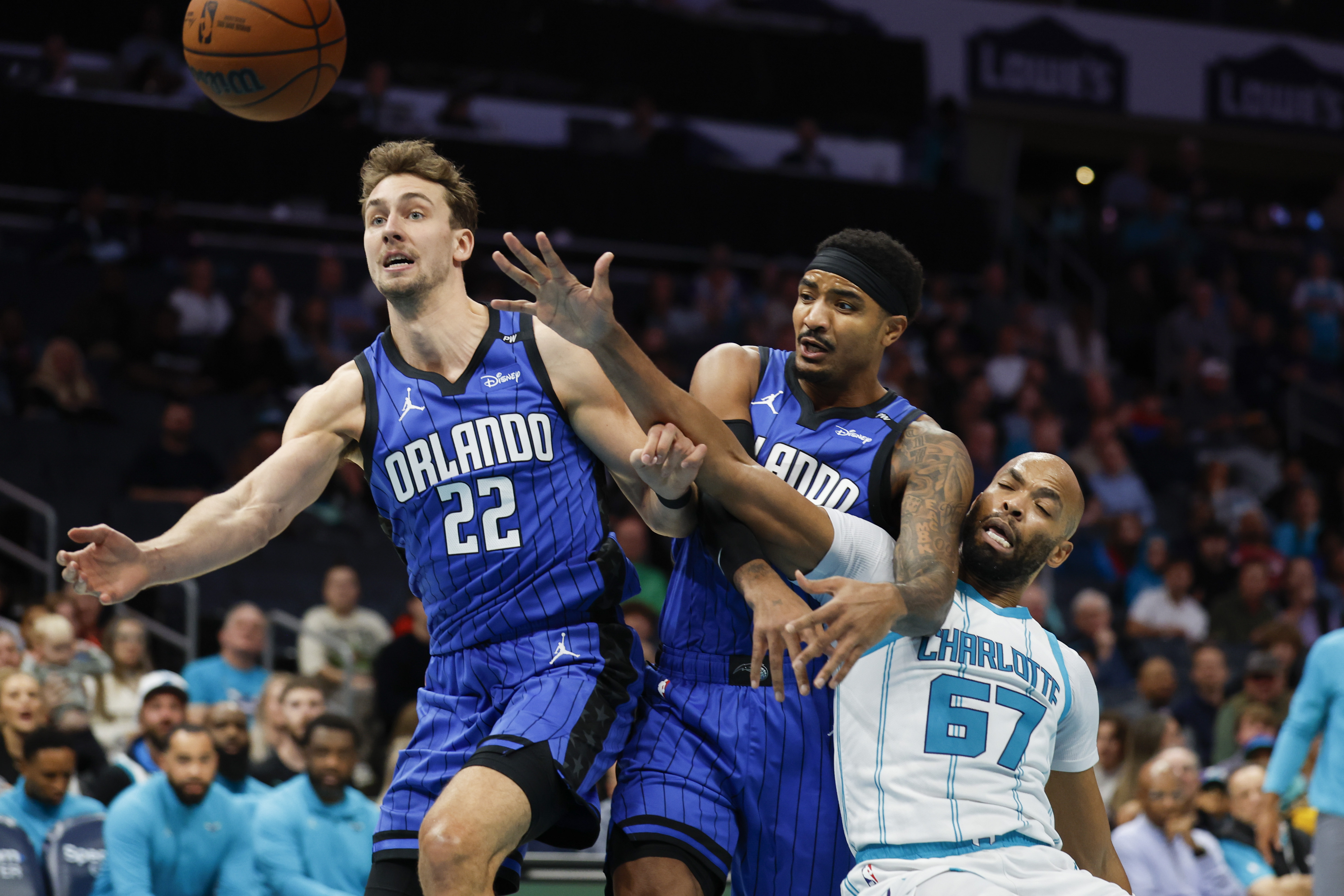Charlotte Hornets forward Taj Gibson (67) battles Orlando Magic forward Franz Wagner (22) and guard Gary Harris, center, for the ball during the first half of an NBA basketball game in Charlotte, N.C., Monday, Nov. 25, 2024.