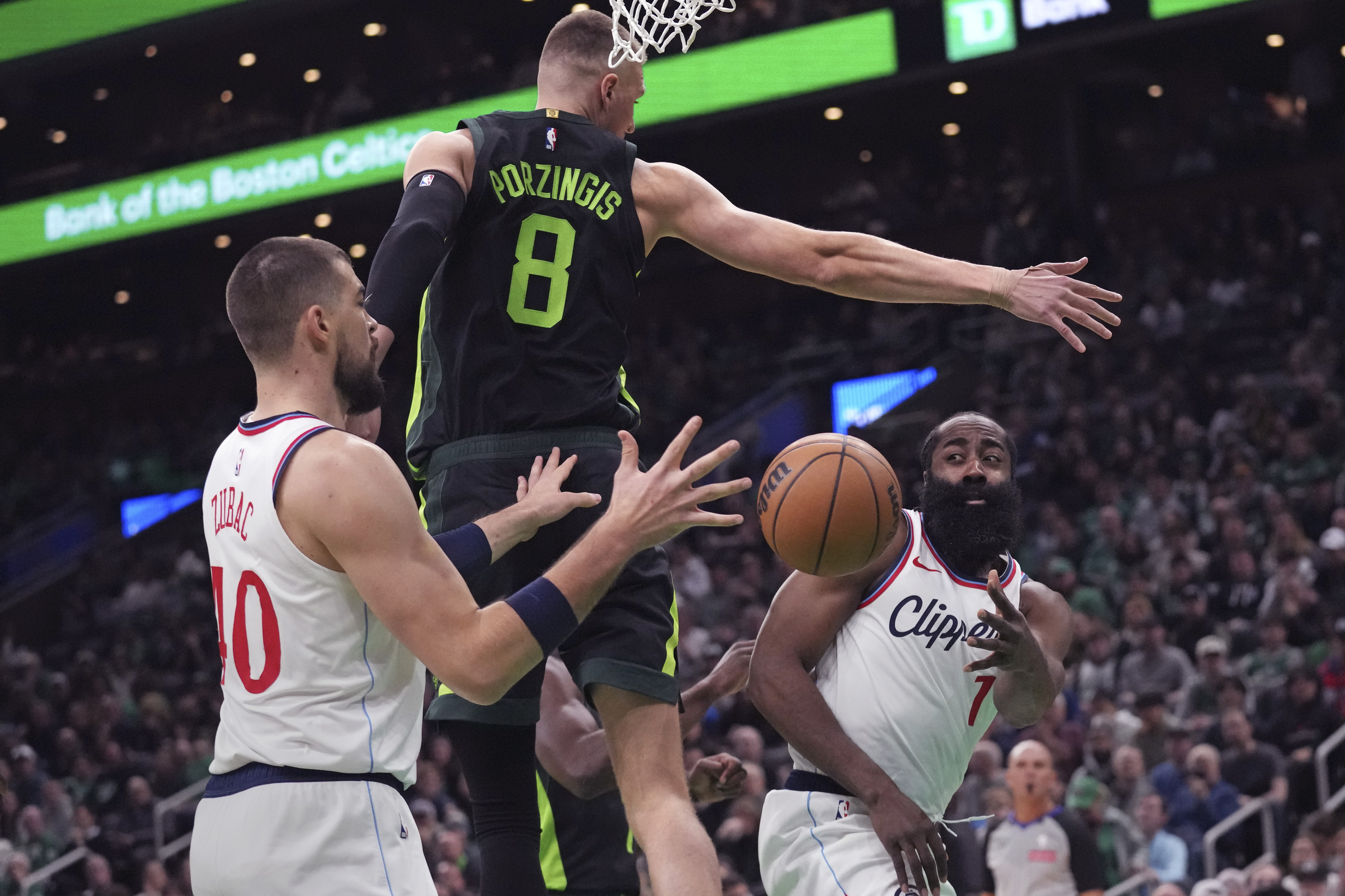 LA Clippers guard James Harden, right, passes the ball behind the back of Boston Celtics center Kristaps Porzingis (8) to Ivica Zubac (40) during the first half of an NBA basketball game, Monday, Nov. 25, 2024, in Boston. 