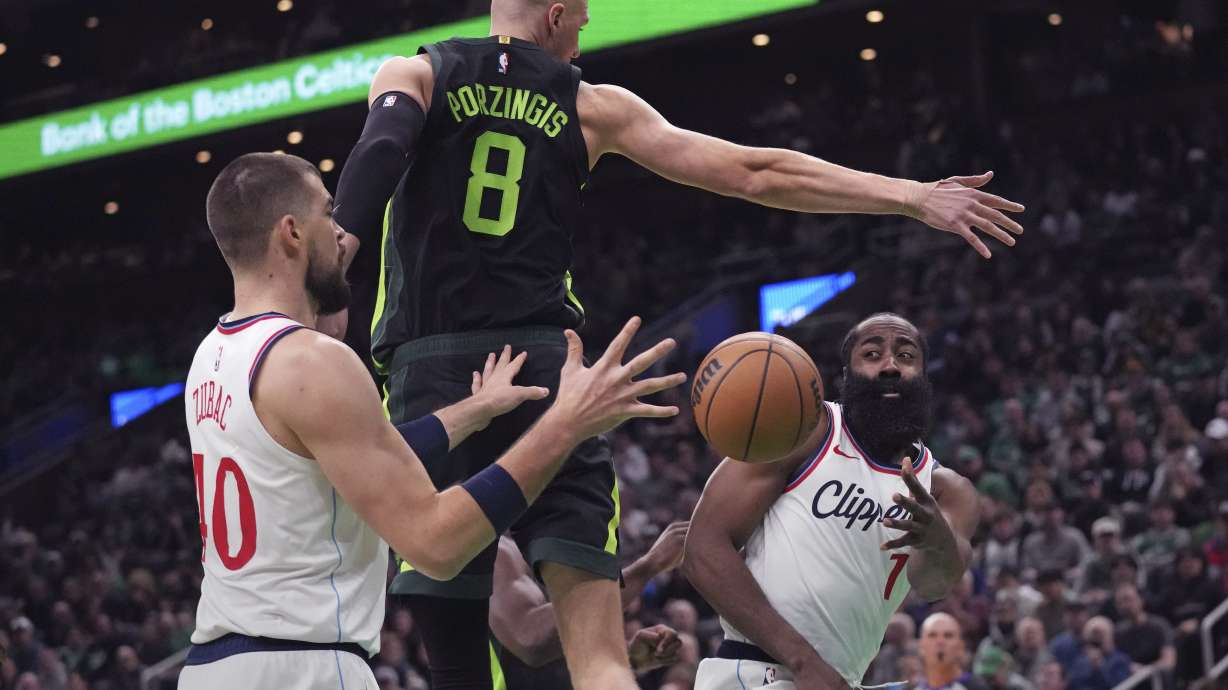 LA Clippers guard James Harden, right, passes the ball behind the back of Boston Celtics center Kristaps Porzingis (8) to Ivica Zubac (40) during the first half of an NBA basketball game, Monday, Nov. 25, 2024, in Boston.