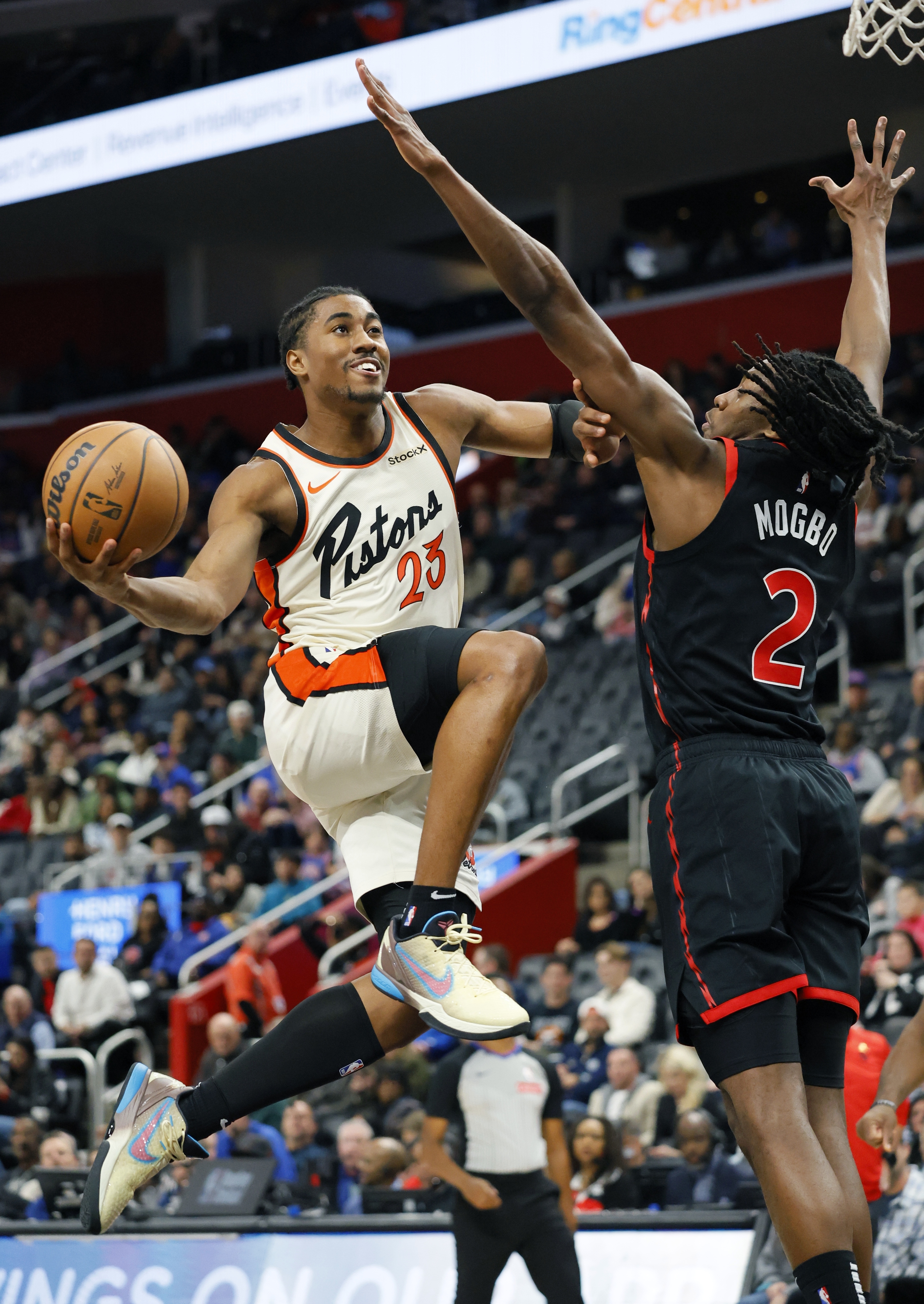 Detroit Pistons guard Jaden Ivey (23) is guarded by Toronto Raptors forward Jonathan Mogbo (2) while going to the basket during the first half of an NBA basketball game Monday, Nov. 25, 2024, in Detroit.