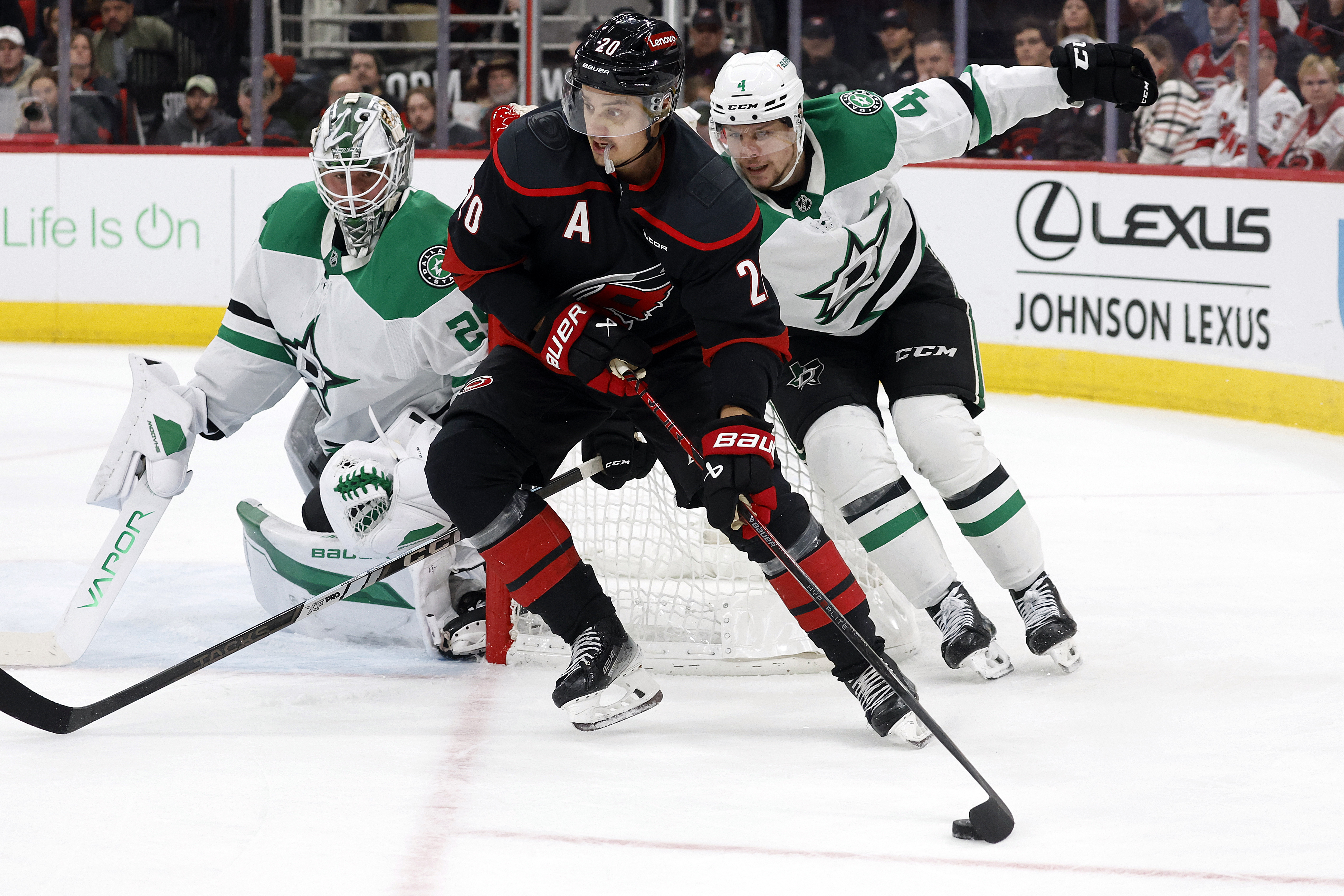 Carolina Hurricanes' Sebastian Aho (20) controls the puck in front of Dallas Stars goaltender Jake Oettinger (29) and Miro Heiskanen (4) during the second period of an NHL hockey game in Raleigh, N.C., Monday, Nov. 25, 2024.