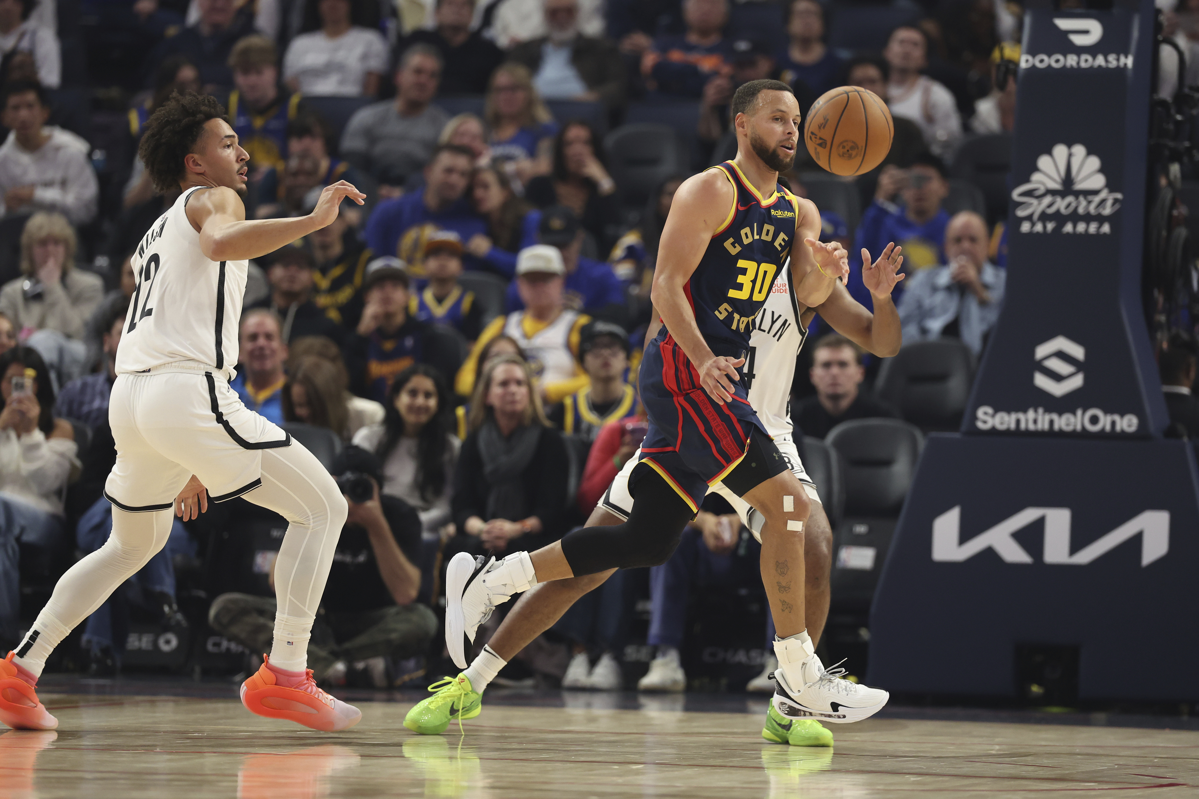 Golden State Warriors guard Stephen Curry (30) passes the ball against Brooklyn Nets forward Jalen Wilson, left, during the first half of an NBA basketball game in San Francisco, Monday, Nov. 25, 2024.