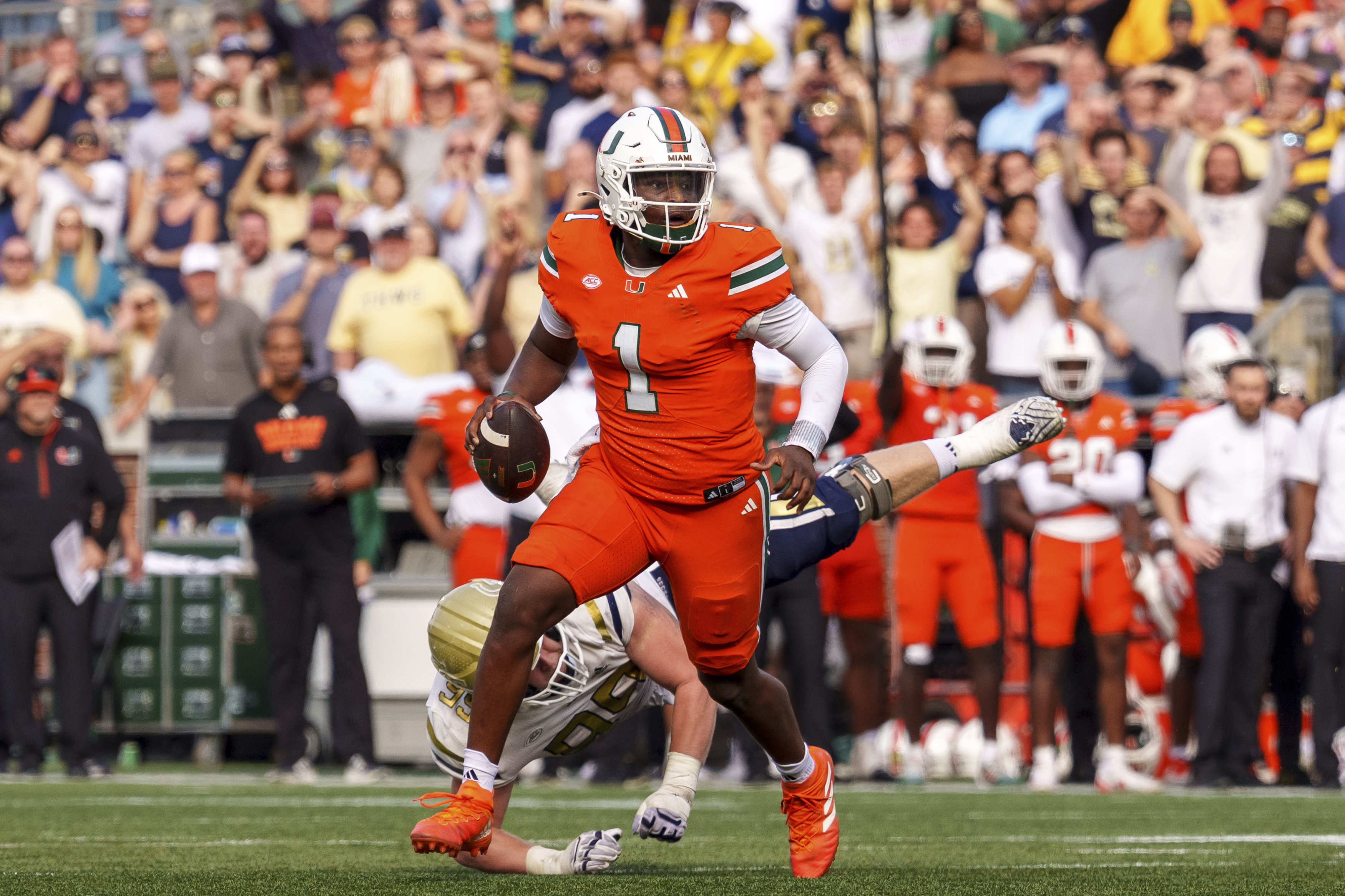 Miami quarterback Cam Ward (1) is rushed out of the pocket by Georgia Tech defensive lineman Jordan van den Berg, behind, during the second half of an NCAA college football game, Saturday, Nov. 9, 2024, in Atlanta.
