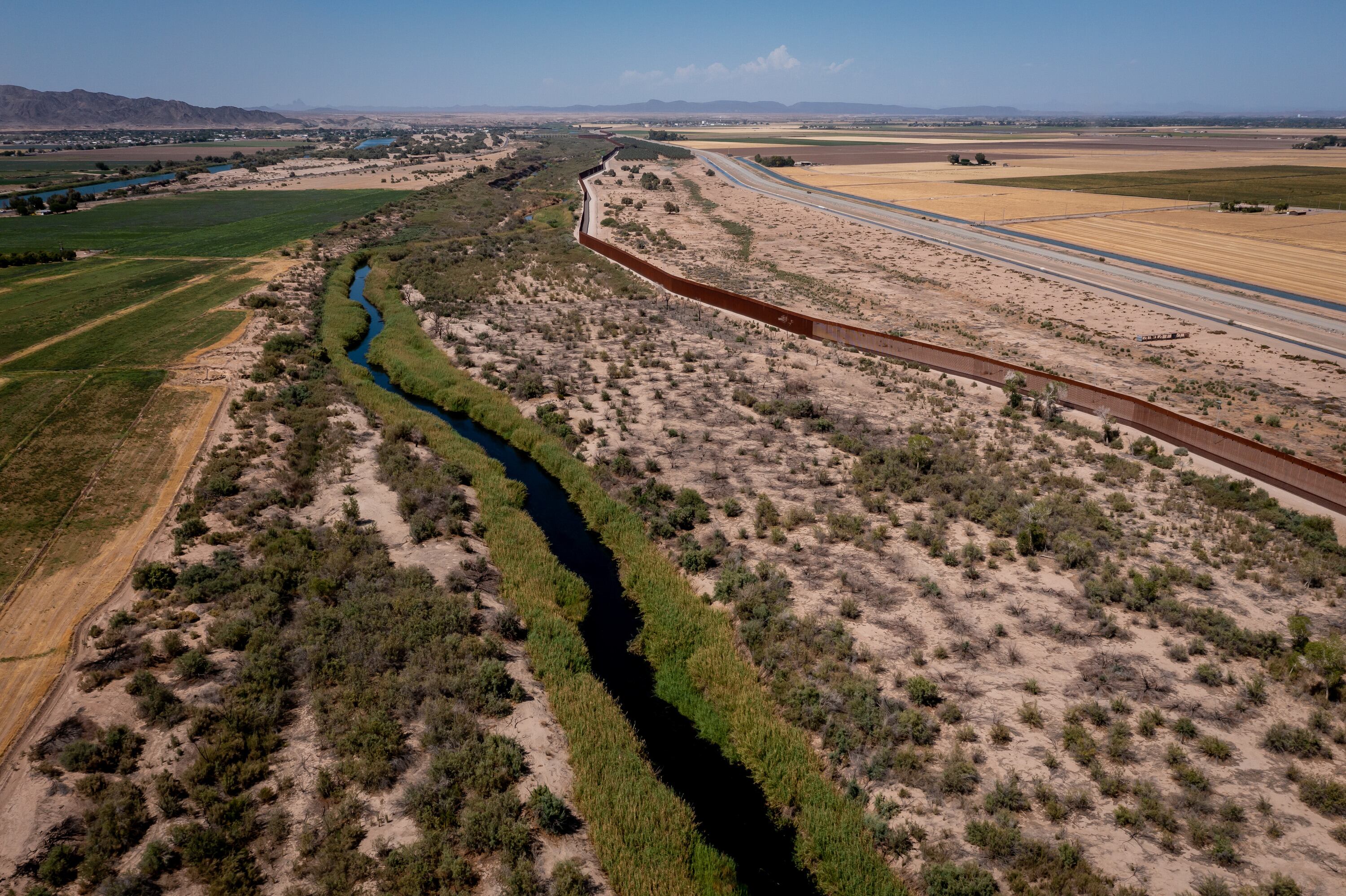 A small amount of water flows in the Colorado River channel after most of it was diverted into an irrigation canal near Los Algodones, Baja California, Mexico, on June 24, 2022. At right is the border wall separating Mexico and the United States.