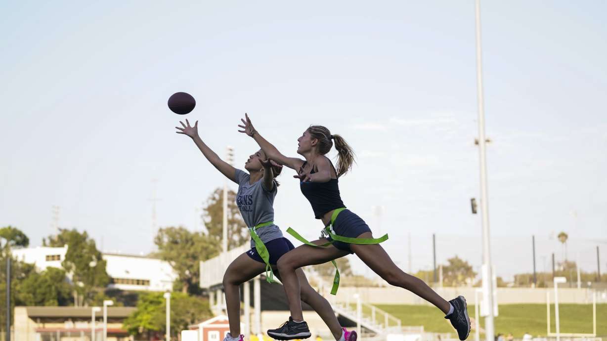 FILE - Syndel Murillo, 16, left, and Shale Harris, 15, reach for a pass as they try out for the Redondo Union High School girls flag football team Thursday, Sept. 1, 2022, in Redondo Beach, Calif.