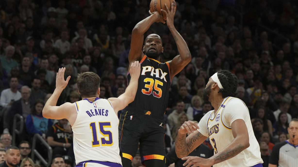 Phoenix Suns forward Kevin Durant shoots over Los Angeles Lakers guard Austin Reaves and forward Anthony Davis (3) during the first half of an NBA basketball game, Tuesday, Nov. 26, 2024, in Phoenix.