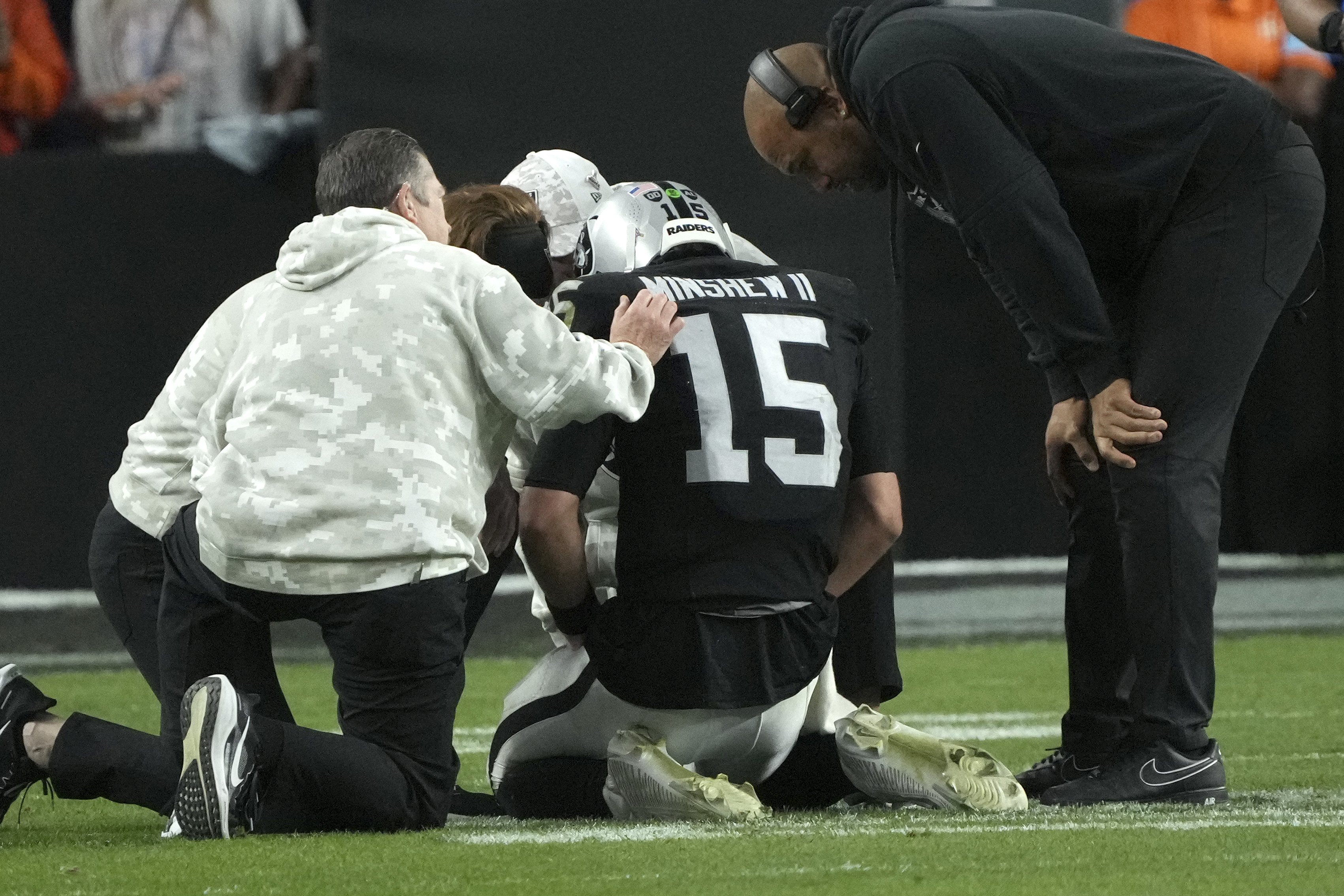 Las Vegas Raiders quarterback Gardner Minshew (15) is assisted by trainers and Head Coach Antonio Pierce, right, after an injury during the second half of an NFL football game against the Denver Broncos, Sunday, Nov. 24, 2024, in Las Vegas. 