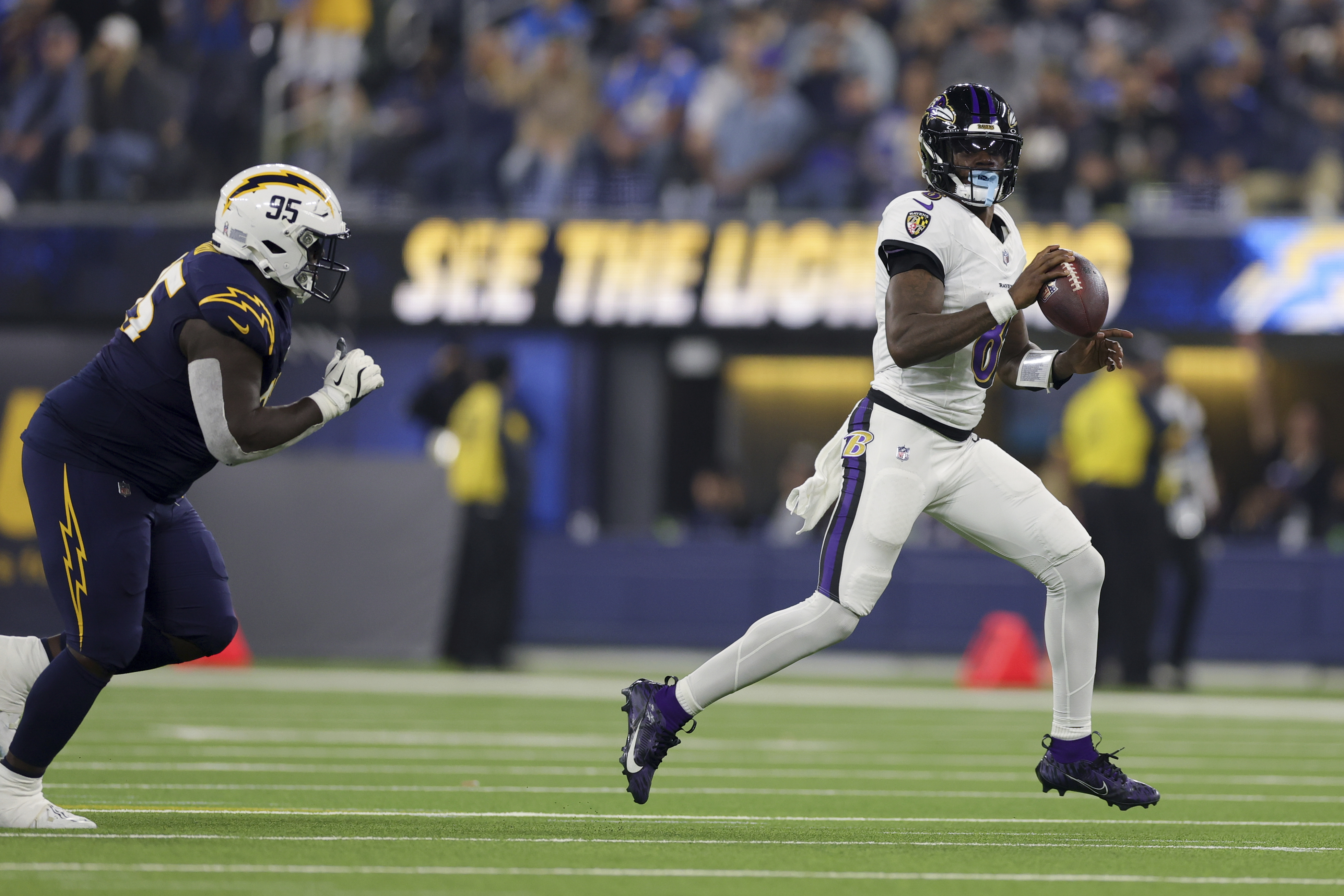 Baltimore Ravens quarterback Lamar Jackson (8) runs past Los Angeles Chargers defensive tackle Poona Ford (95) during the second half of an NFL football game Monday, Nov. 25, 2024, in Inglewood, Calif. 
