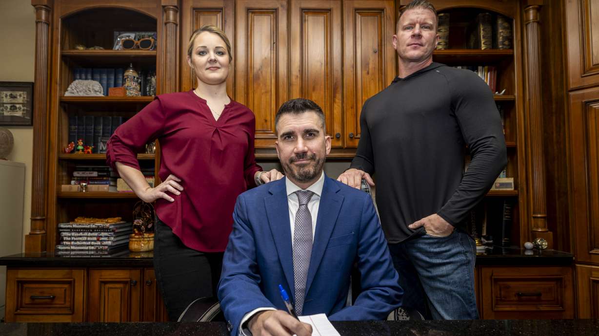 Attorney Thomas Hutchings, center, poses with his clients Sarah and Andy Figorski for a portrait in Salt Lake County on Wednesday.