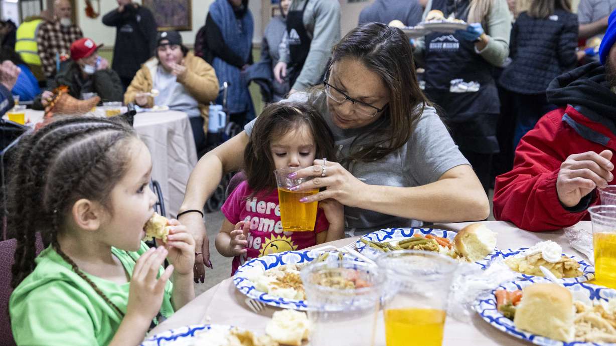 Monica Martinez gives her daughter, Taliyah Trujillo, 2, a drink as her other daughter, Tray Trujillo, 4, eats on her own during the Hope Renewed Thanksgiving Banquet held by the Rescue Mission of Salt Lake in Salt Lake City on Wednesday.