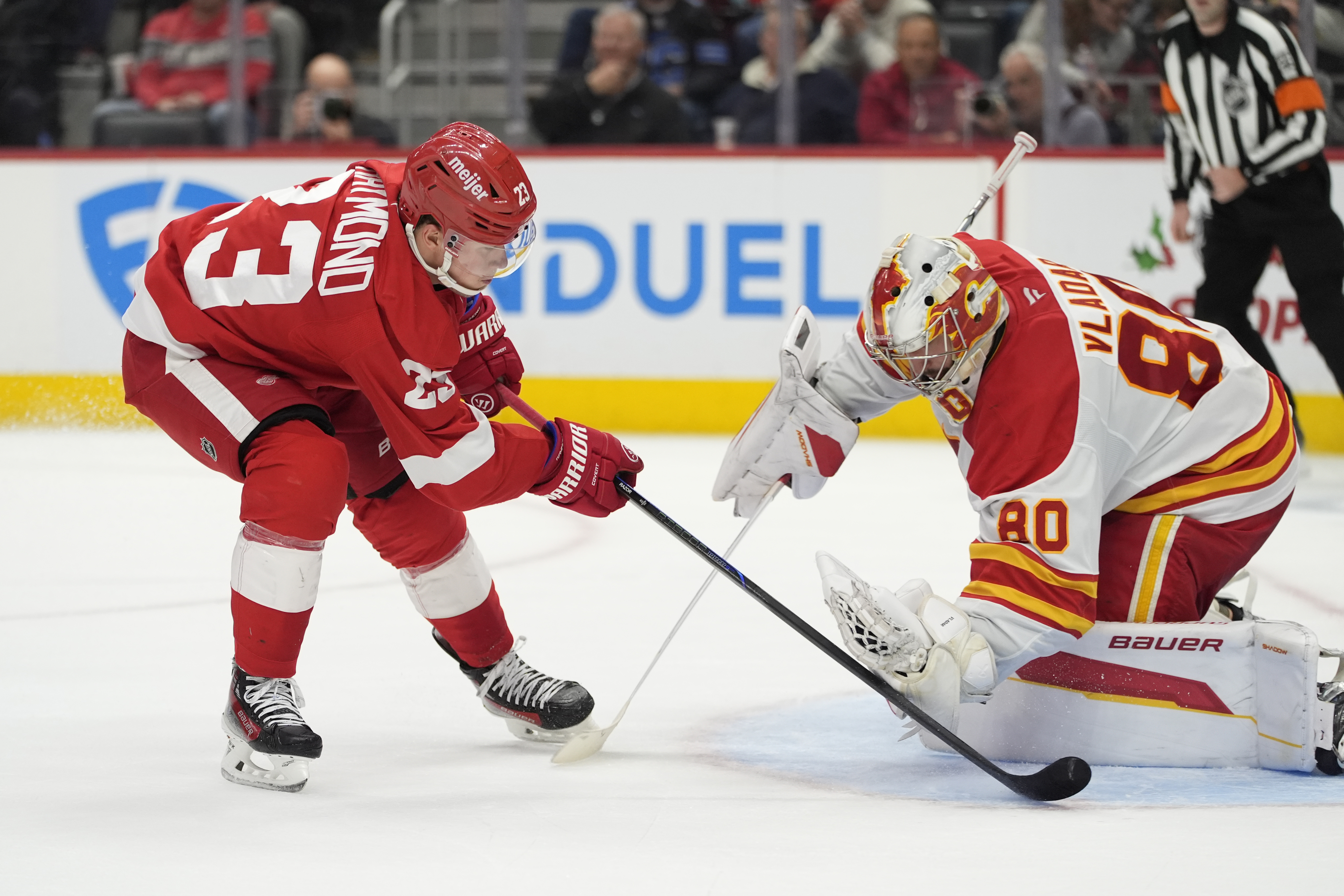 Calgary Flames goaltender Dan Vladar (80) stops a shot by Detroit Red Wings left wing Lucas Raymond (23) during the second period of an NHL hockey game, Wednesday, Nov. 27, 2024, in Detroit.