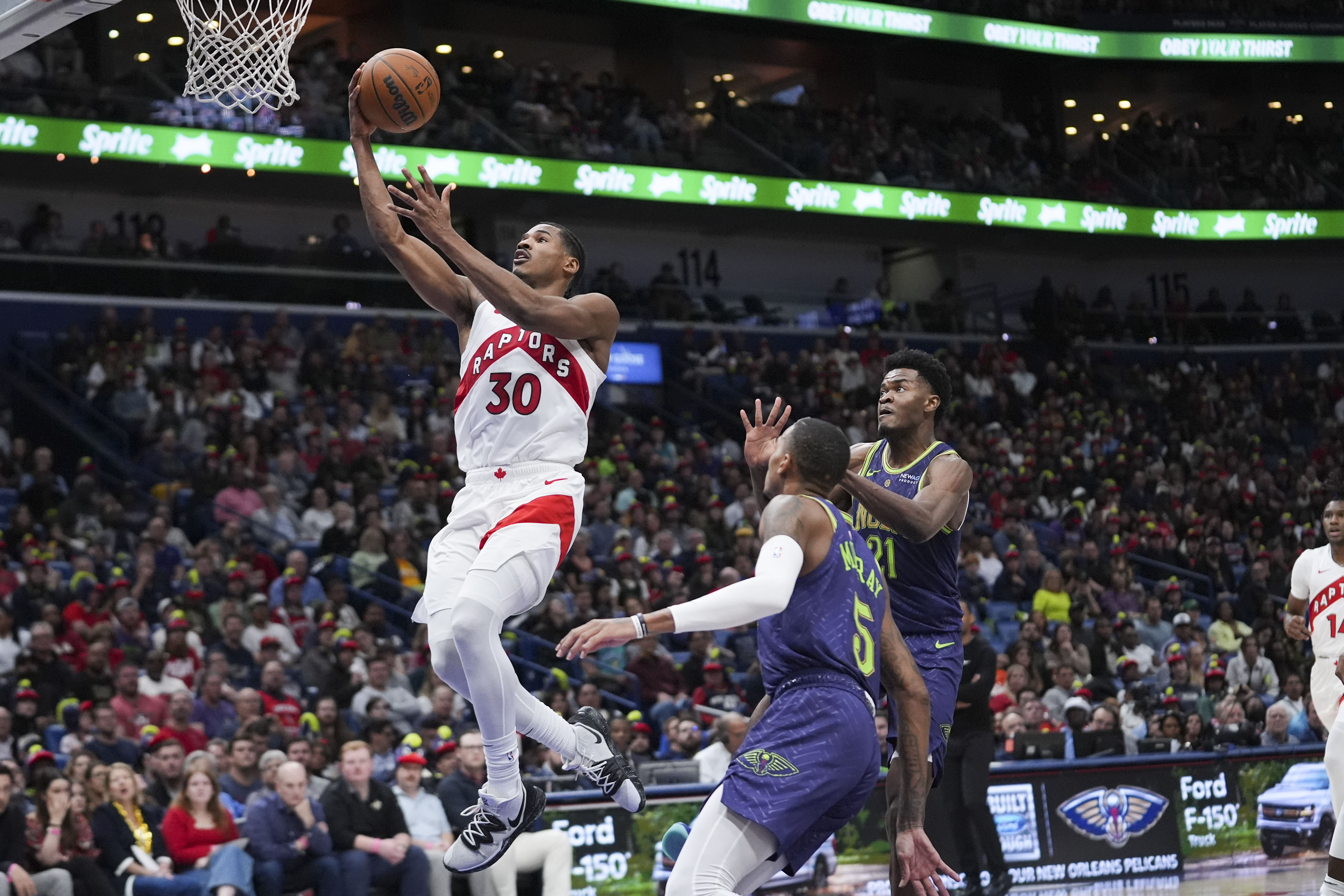 Toronto Raptors guard Ochai Agbaji (30) goes to the basket ahead of New Orleans Pelicans center Yves Missi (21) and guard Dejounte Murray (5) in the first half of an NBA basketball game in New Orleans, Wednesday, Nov. 27, 2024.