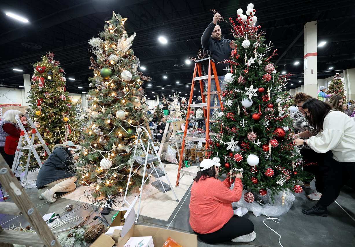 Brandon Muir decorates the Snowballs and Cocoa tree along with others at the 53rd annual Festival of Trees to benefit Intermountain Primary Children’s Hospital patients, at the Mountain America Expo Center in Sandy on Nov. 27, 2023.