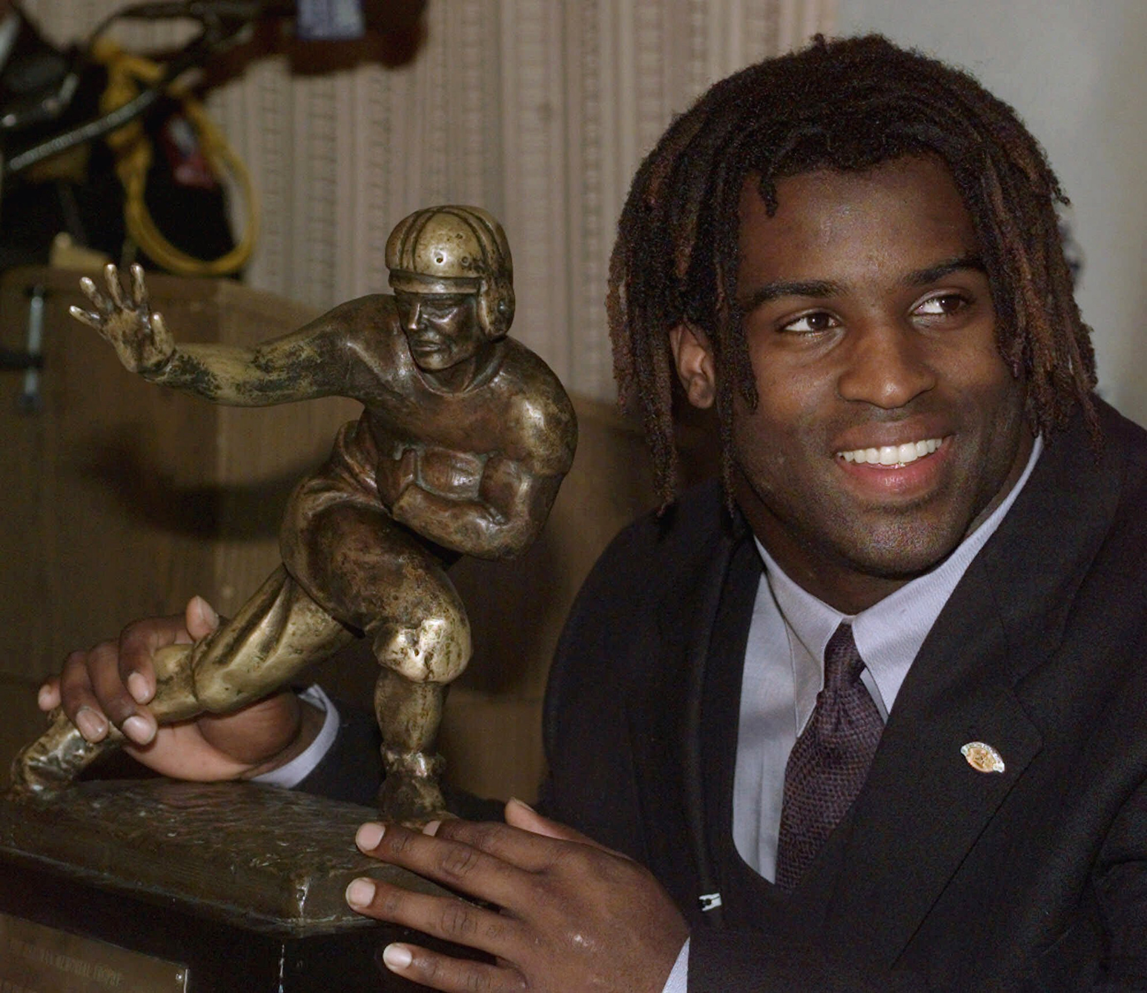 FILE - Texas NCAA college football tailback Ricky Williams poses with the Heisman Trophy at the Downtown Athletic Club in New York, Dec. 12, 1998. 