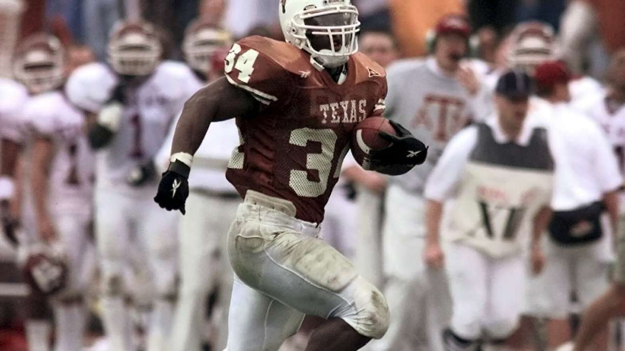 FILE - Texas running back Ricky Williams breaks the all-time NCAA college rushing record as he runs past the Texas A&M bench for a 60-yard touchdown during the first quarter in Austin, Texas, Nov. 27, 1998.