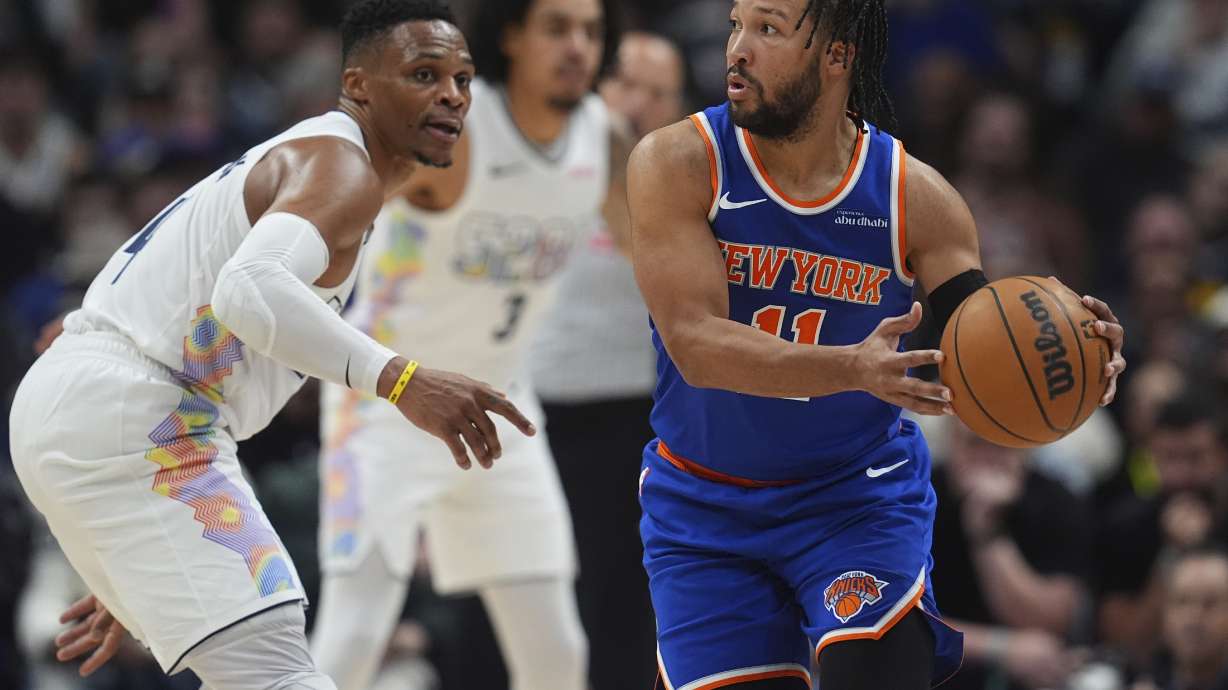 New York Knicks guard Jalen Brunson, right, looks to pass the ball as Denver Nuggets guard Russell Westbrook defends in the second half of an NBA basketball game Monday, Nov. 25, 2024, in Denver.