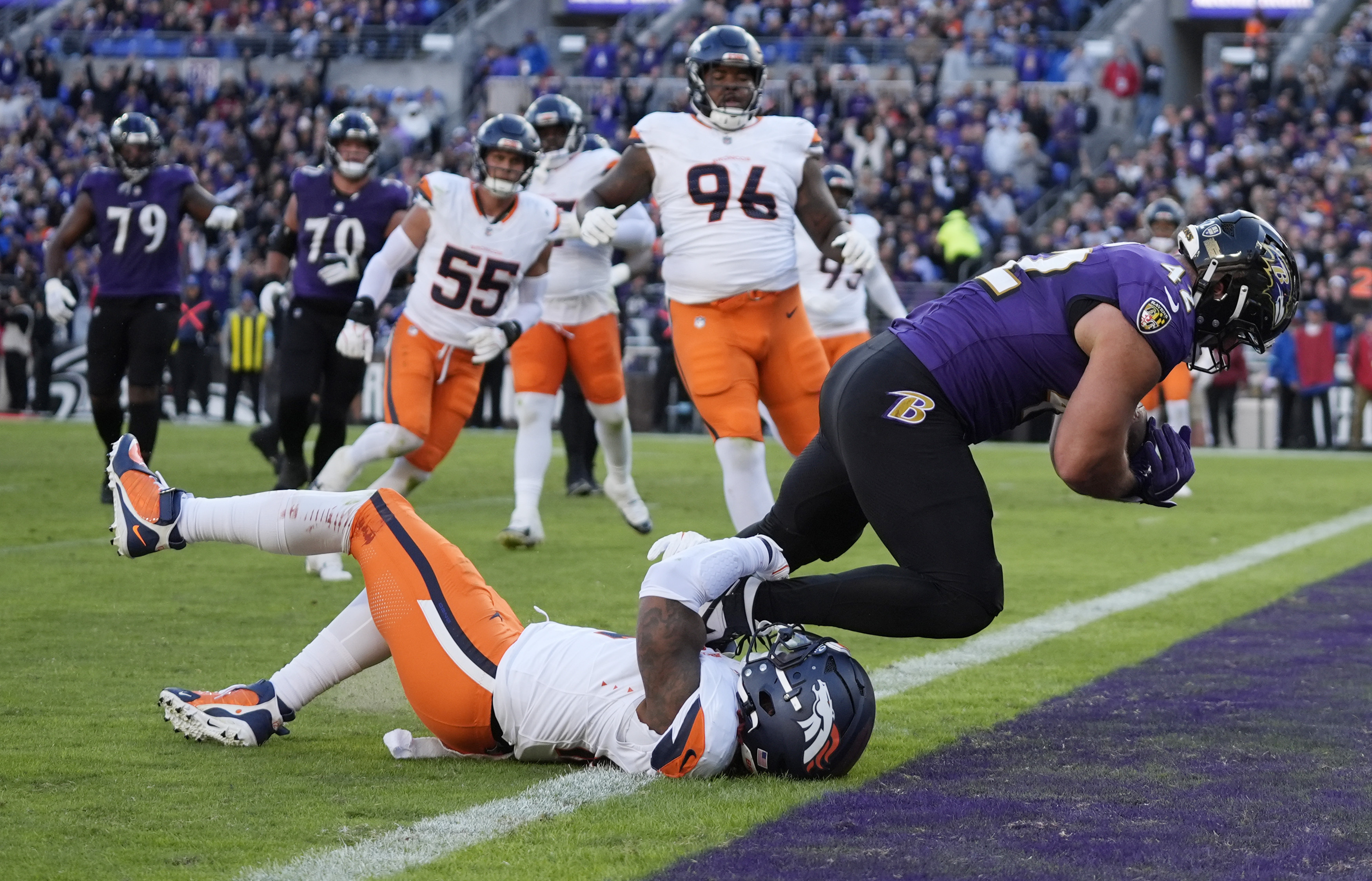Baltimore Ravens fullback Patrick Ricard, right, tumbles into the end zone for a touchdown as Denver Broncos linebacker Kwon Alexander defends in the second half of an NFL football game Sunday, Nov. 3, 2024, in Baltimore.