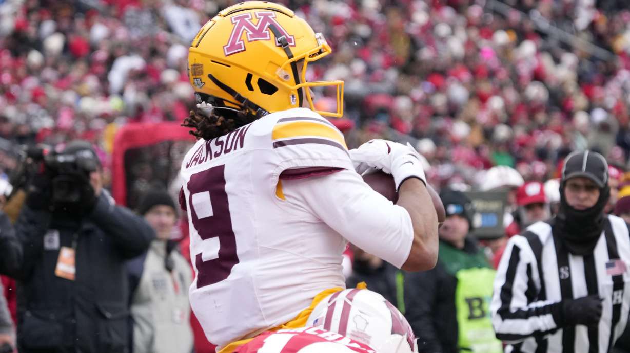 Minnesota wide receiver Daniel Jackson (9) catches a touchdown pass as he is tackled by Wisconsin safety Preston Zachman (14) during the first half of an NCAA college football game Friday, Nov. 29, 2024, in Madison, Wis.