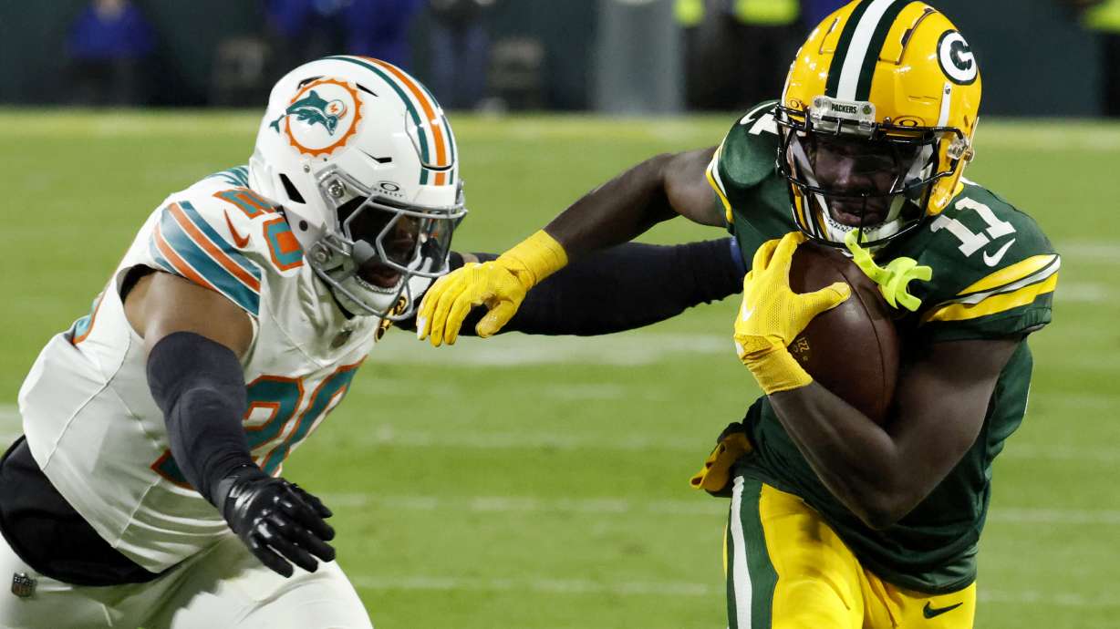 Green Bay Packers wide receiver Jayden Reed (11) runs from Miami Dolphins linebacker Jordyn Brooks (20) during a 12-yard touchdown reception in the first half of an NFL football game Thursday, Nov. 28, 2024, in Green Bay, Wis.
