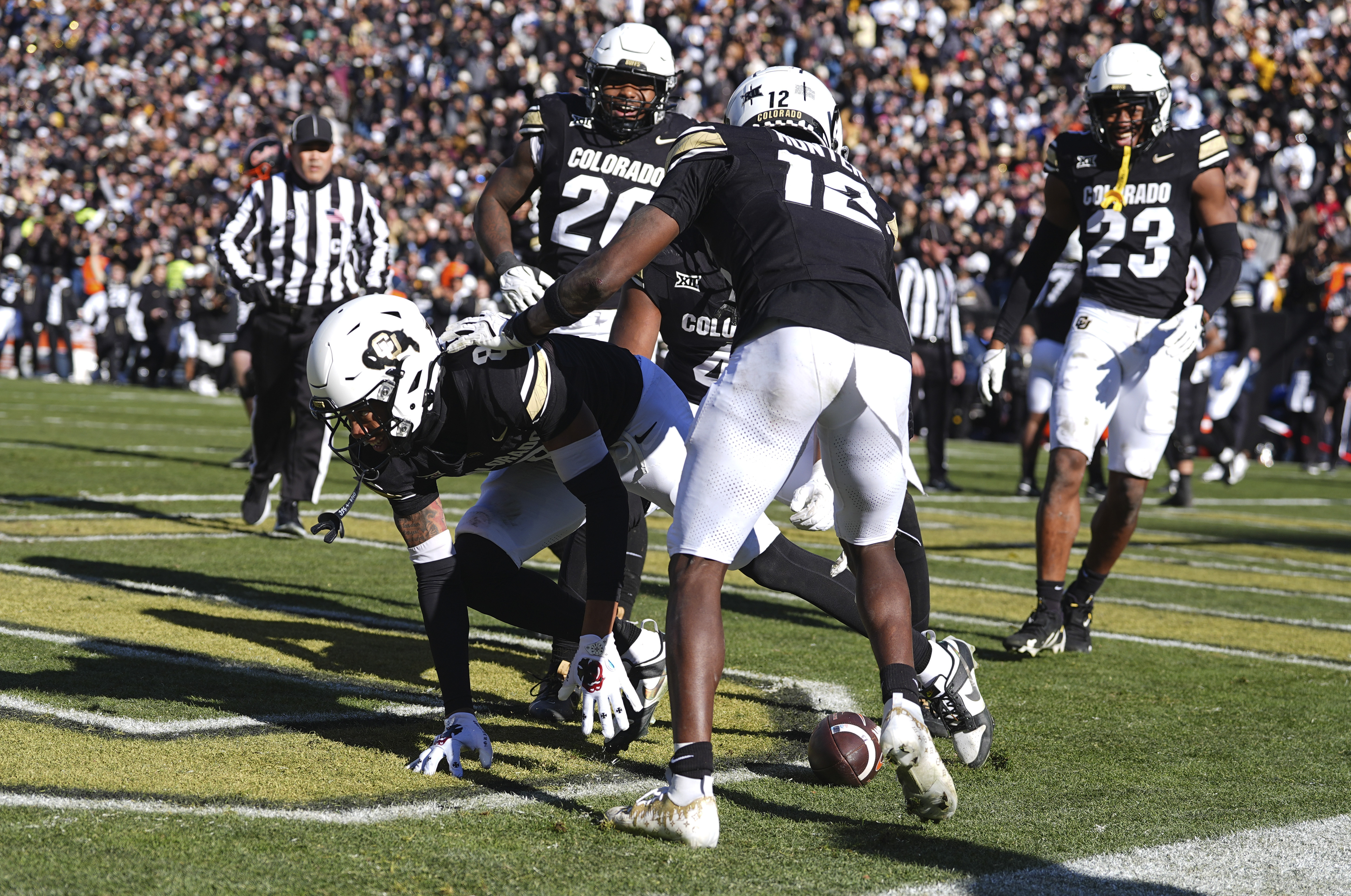 Colorado cornerback DJ McKinney, center, gestures after placing the ball in the end zone following his interception return for a score as linebacker LaVonta Bentley, back, and Travis Hunter look on in the second half of an NCAA college football game against Oklahoma State, Friday, Nov. 29, 2024, in Boulder, Colo.