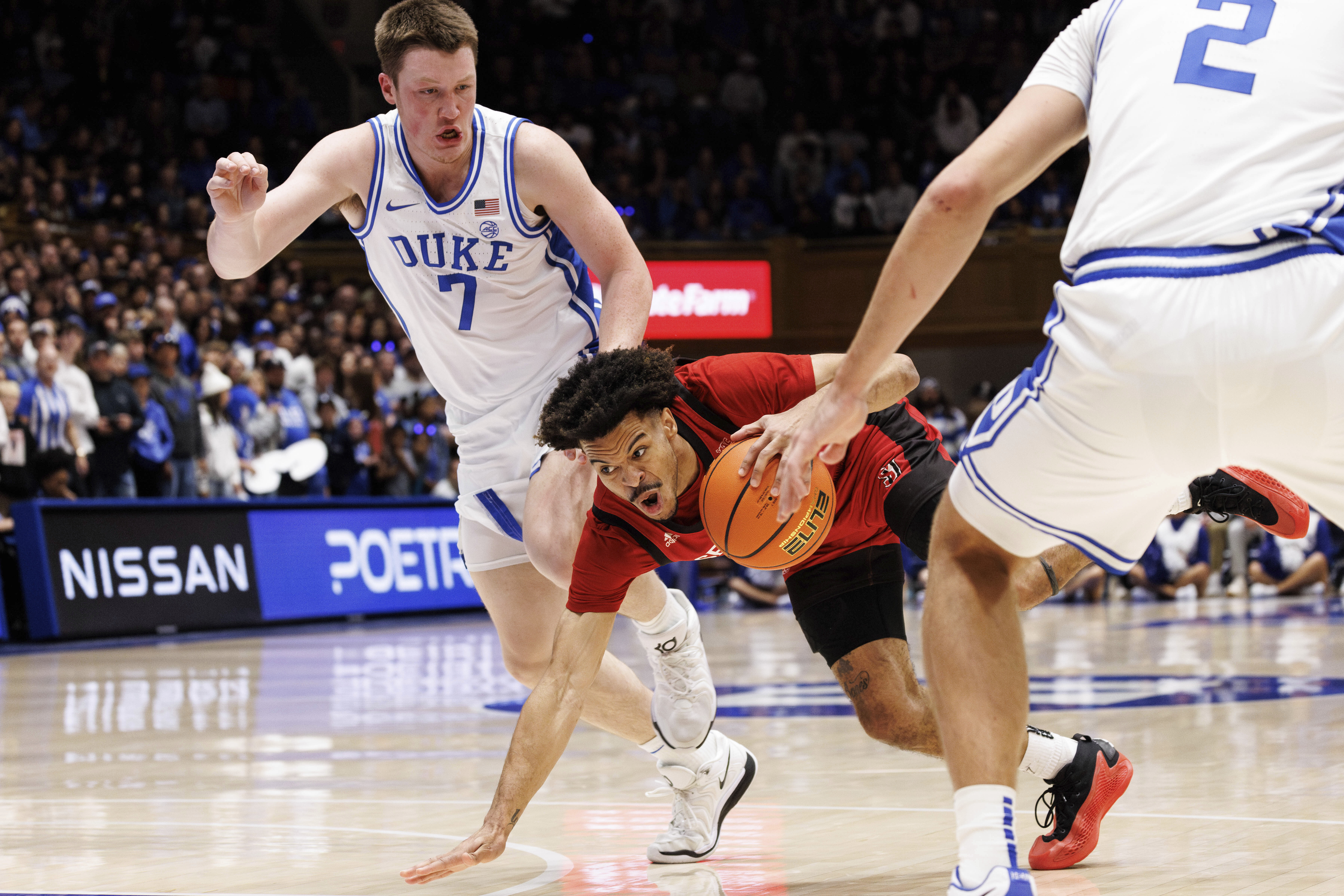 Seattle's Paris Dawson, center, falls while handling the ball as Duke's Kon Knueppel (7) defends during the first half of an NCAA college basketball game in Durham, N.C., Friday, Nov. 29, 2024. 