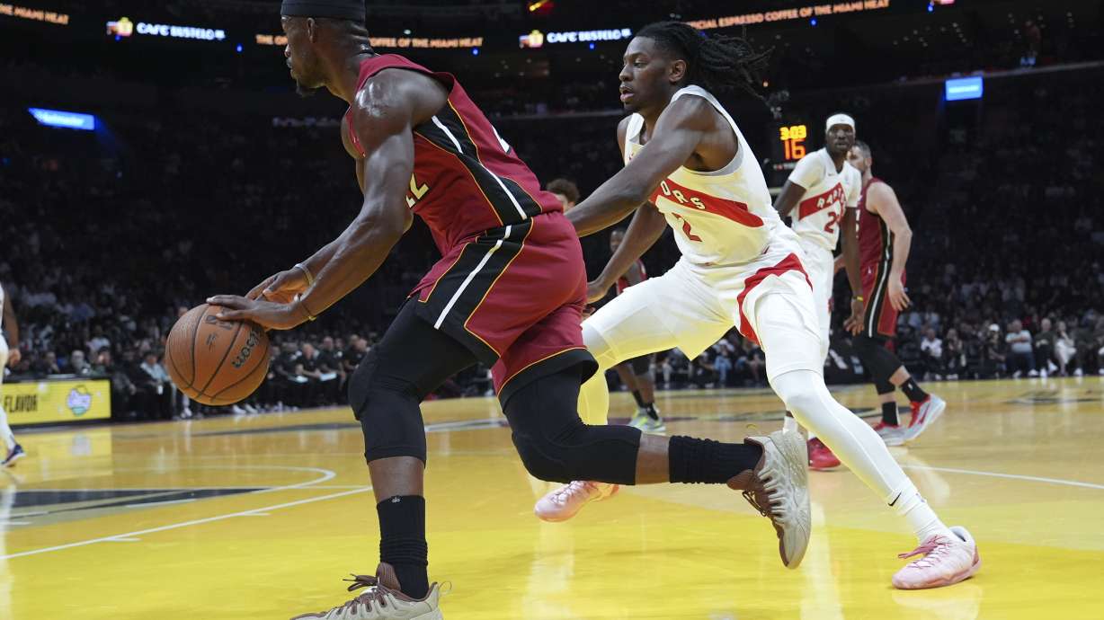 Miami Heat forward Jimmy Butler, left, drives to the basket as Toronto Raptors forward Jonathan Mogbo, right, defends during the first half of an Emirates NBA Cup basketball game, Friday, Nov. 29, 2024, in Miami.