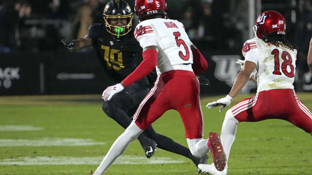 Utah cornerback Zemaiah Vaughn (5) runs back an interception for a 60-yard touchdown past Central Florida wide receiver Jarrad Baker, left, during the first half of an NCAA college football game, Friday, Nov. 29, 2024, in Orlando, Fla.