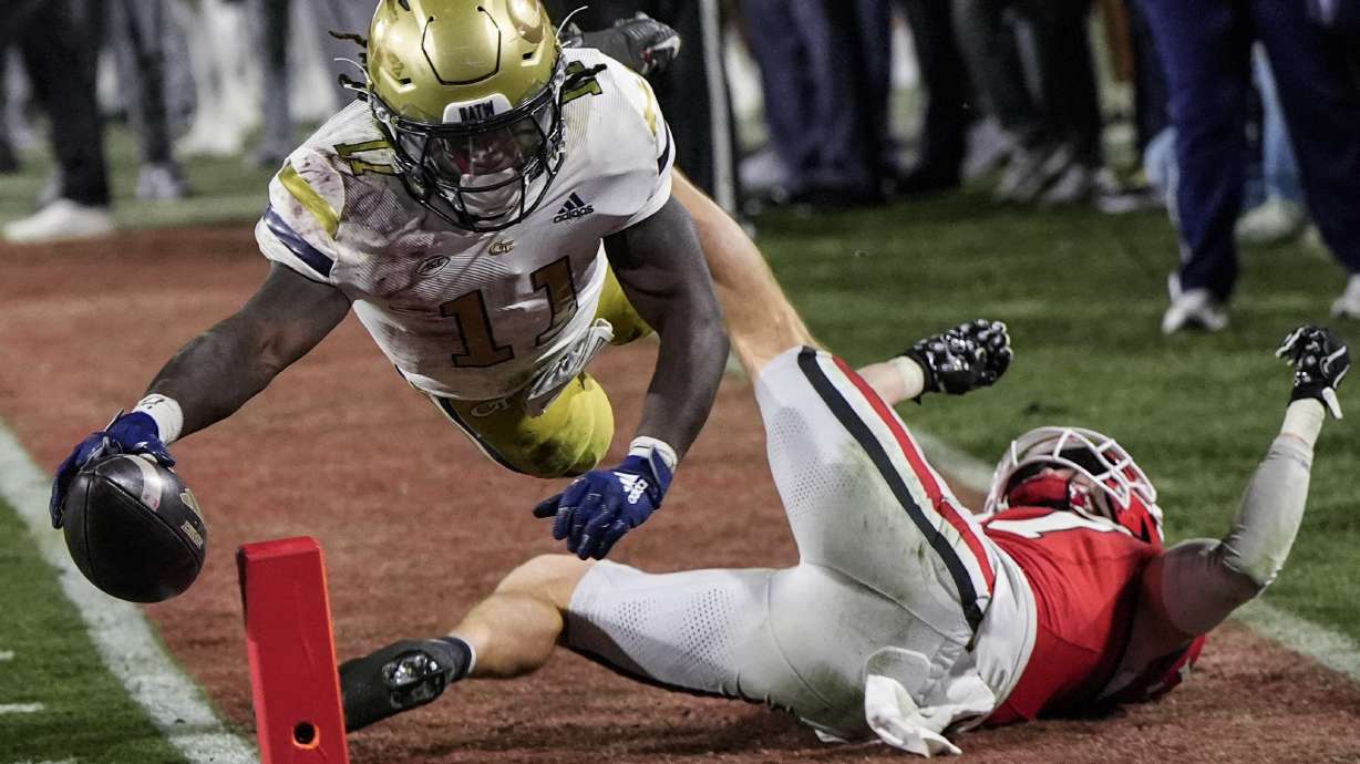 Georgia Tech running back Jamal Haynes (11) leaps into the end zone for a touchdown against Georgia defensive back Dan Jackson (17) during the first half of an NCAA college football game, Friday, Nov. 29, 2024, in Athens, Ga.