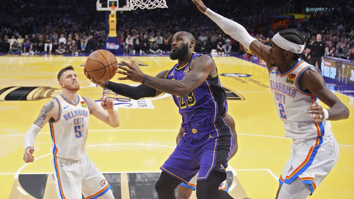 Los Angeles Lakers forward LeBron James, center, shoots as Oklahoma City Thunder center Isaiah Hartenstein, left, and guard Shai Gilgeous-Alexander defend during the first half of an Emirates NBA Cup basketball game, Friday, Nov. 29, 2024, in Los Angeles.